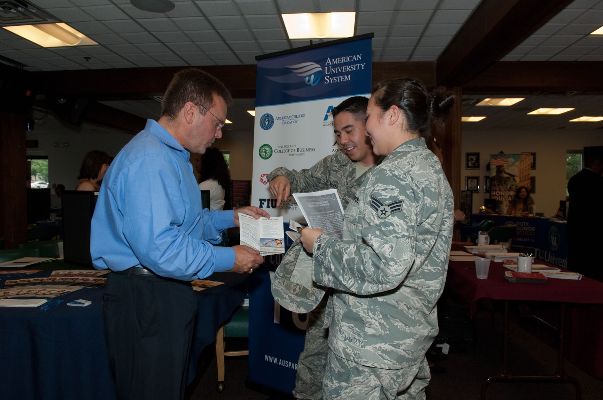 HANSCOM AIR FORCE BASE, Mass. -- David Saba (left), from American University System, speaks with Staff Sgt. Sean McKee and Senior Airman Christina McKenna during the Education Fair at the Minuteman Club on July 22. (U.S. Air Force photo by Rick Berry)