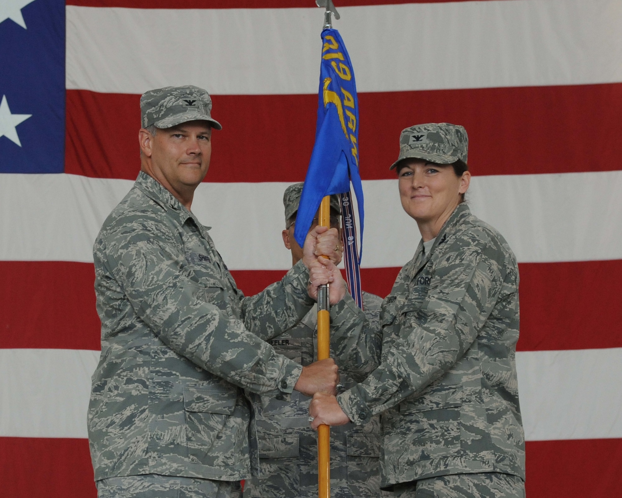 Col. Don Shaffer, 319th Air Refueling Wing commander, passes the guideon to the new 319th Mission Support Group commander, Col. Tammy Knierm, as she assumes command during the change-of-command ceremony July 29.  Colonel Knierm replaces Col. Joseph Douez as the mission support group commander and will be responsible for all wing support missions on base, including civil engineering and security forces. (U.S. AIr Force photo/Tech. Sgt. Johnny Saldivar)