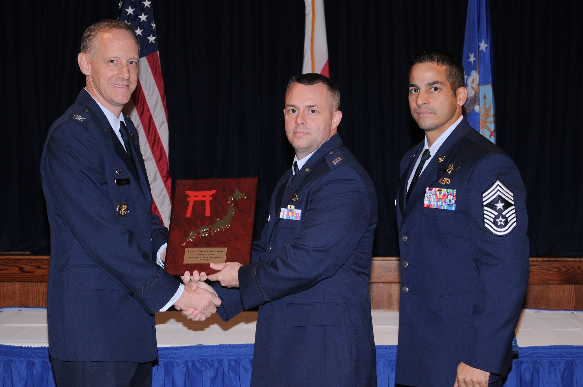 YOKOTA AIR BASE, Japan -- Captain Michael Spalding, 375th Maintenance Squadron operations officer, accepts the Team Yokota Company Grade Officer of the Quarter Award from Col. Otto Feather, 374th Airlift Wing commander, and Chief Master Sgt. Benjamin Caro, 374th AW command chief, during a Quarterly Awards Ceremony held at the Enlisted Club here July 27. Capt. Spalding also received the Samurai CGO of the Quarter Award. (U.S. Air Force photo/ Airman 1st Class Katrina R. Menchaca)