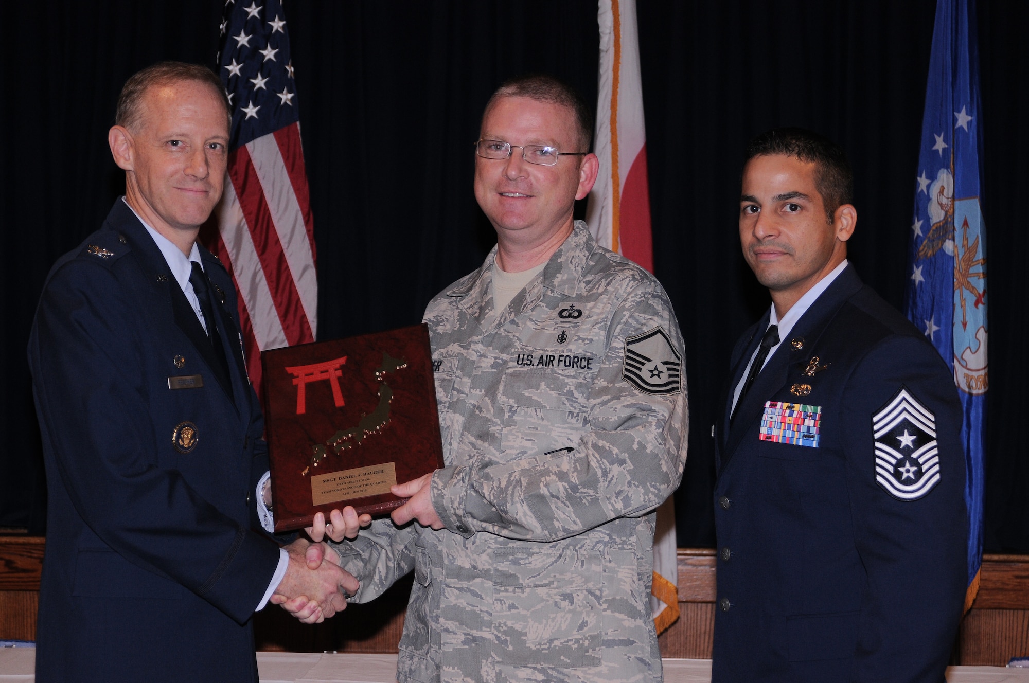 YOKOTA AIR BASE, Japan - Master Sgt. Daniel Hauger, 374th Operations Support Squadron assistant radar approach control (RAPCON) chief controller, accepts the Team Yokota Senior NCO of the Quarter Award from Col. Otto Feather, 374th Airlift Wing commander, and Chief Master Sgt. Benjamin Caro, 374th AW command chief, during a Quarterly Awards Ceremony held at the Enlisted Club here July 27. Sergeant Hauger also received the Samurai SNCO of the Quarter Award. (U.S. Air Force photo/ Airman 1st Class Katrina R. Menchaca)