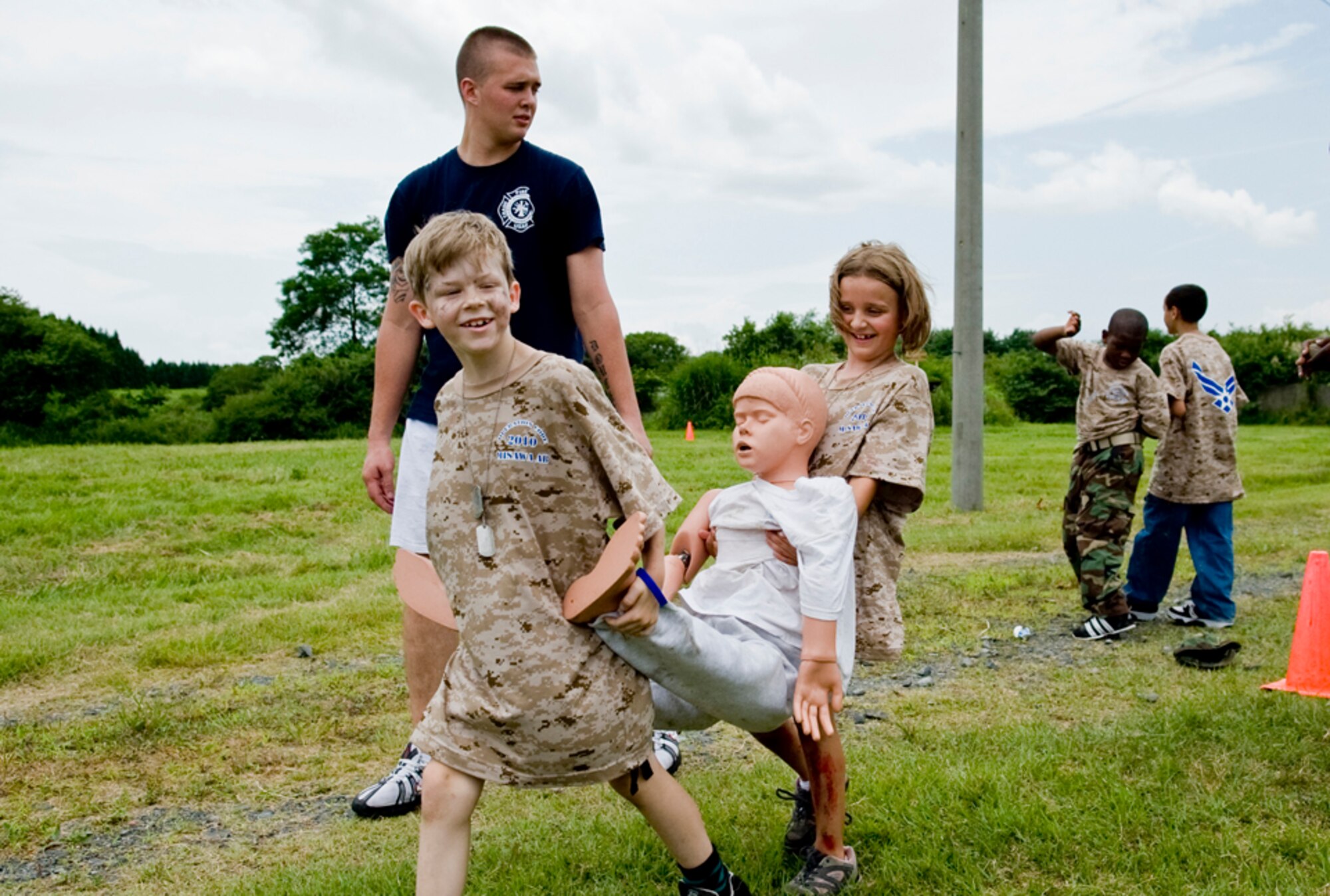 Bradley Hester, 8, son of Maj. Ian Hester, and Maddy Ellis, 7, daughter of Capt. Ian Ellis, carry a dummy during rescue training drills taught by 35th Civil Engineer Squadron fire fighter, Senior Airman Mike Ducet,  July 24, during Misawa’s first Operation Children on Deployment Exercise. Operation CODE, hosted by the Airman and Family Readiness Center, is designed to share the deployment process with military children. (U.S. Air Force photo/ Senior Airman Jessica Lockoski)