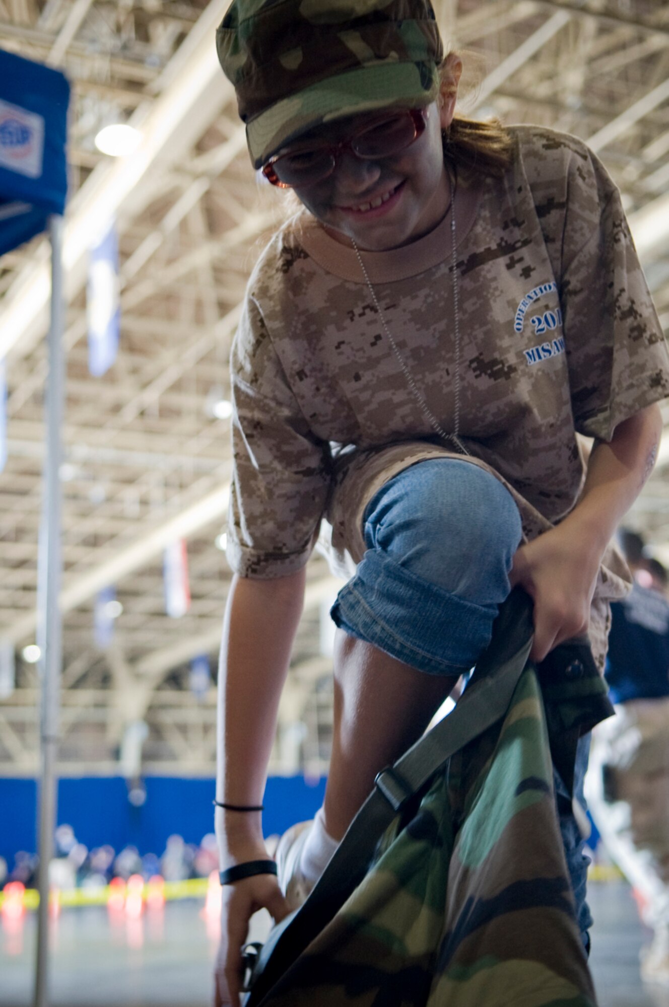 Kierstyn, 10, daughter of Staff Sgt. Sean Day, jumps into chemical suit pants, July 24, to learn what her father takes with him on a deployment during Misawa’s first Operation Children on Deployment Exercise event. Operation CODE, hosted by the Airman and Family Readiness Center, is geared to share the deployment process with military children. (U.S. Air Force photo/ Senior Airman Jessica Lockoski) 