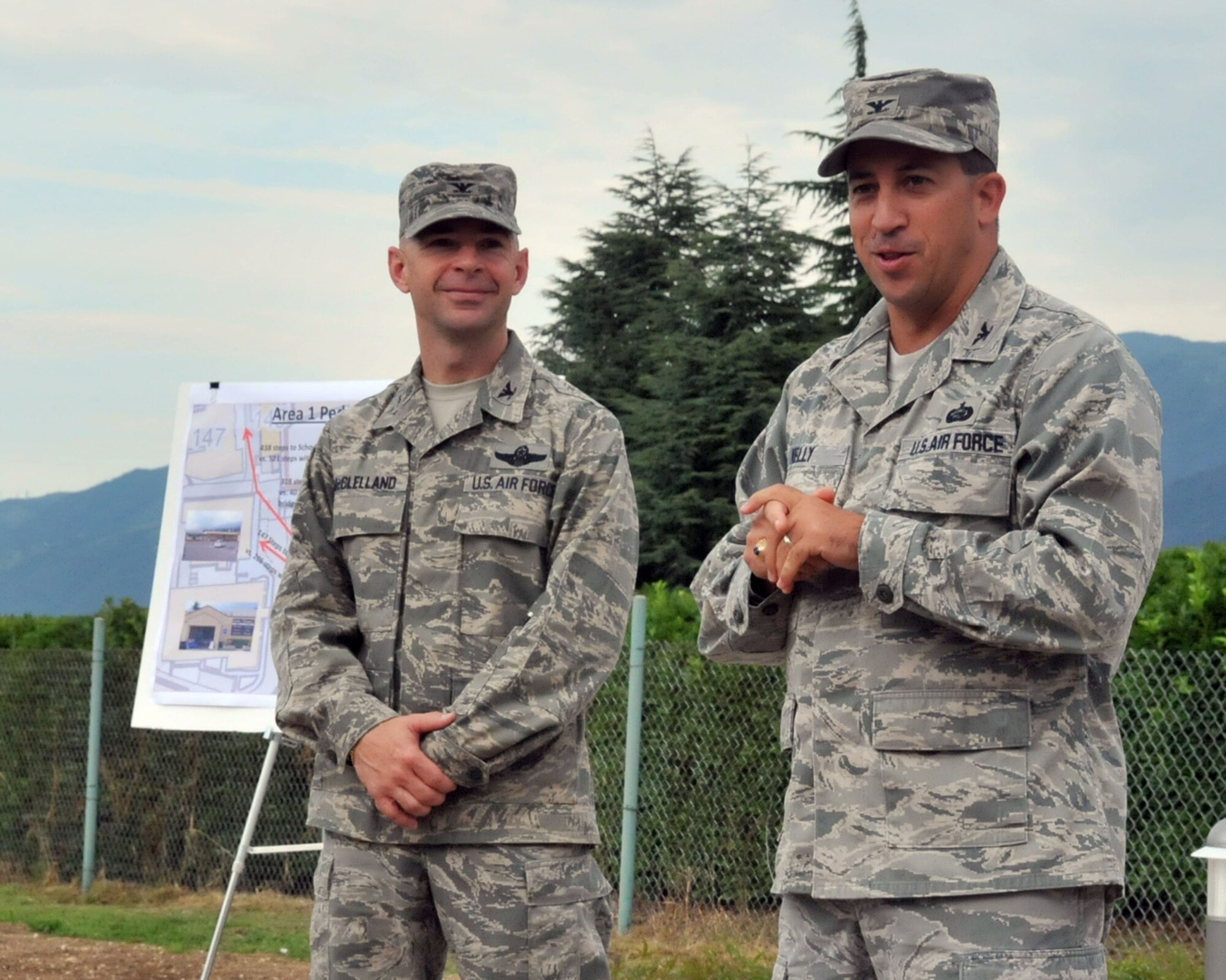 Col. Brian Kelly, 31st Mission Support Group commander, addresses Team Aviano as Col. Patrick McClelland, 31st Fighter Wing commander, looks on during a ribbon-cutting ceremony for the new pedestrian bridge July 27 in Area 1. The structure connects the parking lot in the upper perimeter with the main Shoppette parking lot. (U.S. Air Force photo/Staff Sgt. MercedesKimble Crossland)