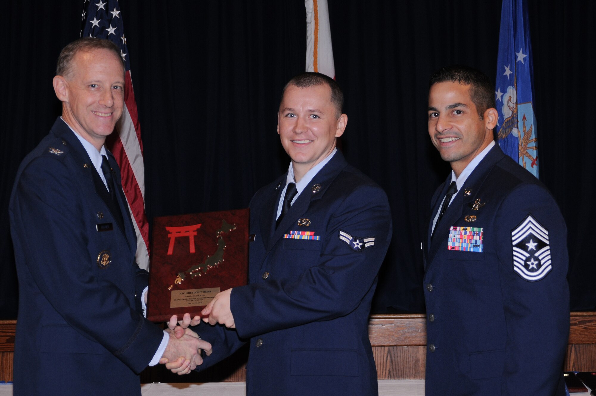 YOKOTA AIR BASE, Japan ? Airman 1st Class Sheldon Dunn, 374th Civil Engineer Squadron structural apprentice, accepts the Team Yokota Airman of the Quarter Award from Col. Otto Feather, 374th Airlift Wing commander, and Chief Master Sgt. Benjamin Caro, 374th AW command chief, during a Quarterly Awards Ceremony held at the Enlisted Club here July 27. Airman Dunn also received the Samurai Airman of the Quarter Award. (U.S. Air Force photo/ Airman 1st Class Katrina R. Menchaca)