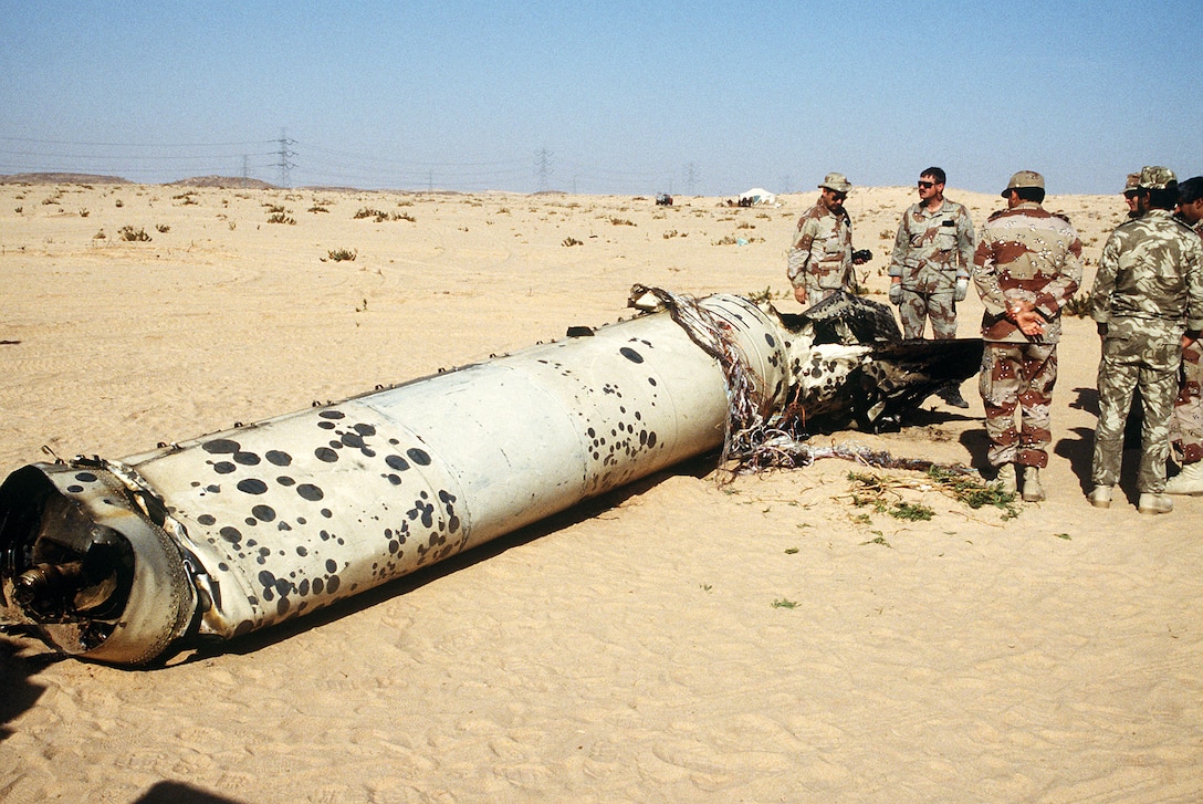 Military personnel examine the tail section of a Scud missile shot down in the desert by an MIM-104 Patriot tactical air defense missile during Operation Desert Storm.