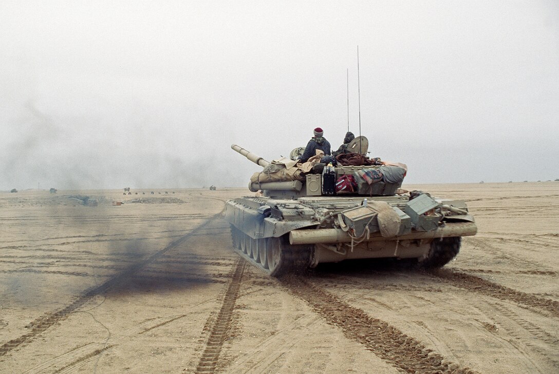 Members of the Coalition forces drive a T-72 main battle tank along a channel cleared of mines during Operation Desert Storm.