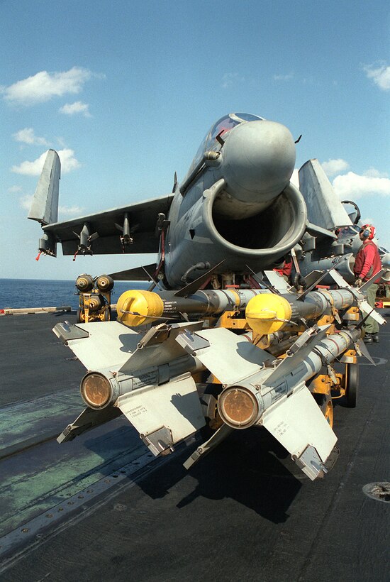 An ordnanceman prepares to load AIM-9 Sidewinder missiles, foreground, and Mark 82 500 lb. bombs on an Attack Squadron 72 (VA-72) A-7E Corsair II aircraft.  The Corsair, based aboard the aircraft carrier USS JOHN F. KENNEDY (CV-67), will be used to make strikes against Iraqi targets during Operation Desert Storm.