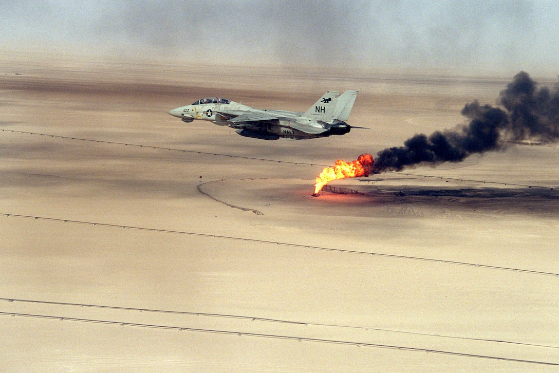 A Fighter Squadron 114 (VF-114) F-14A Tomcat aircraft flies over an oil well still burning in the aftermath of Operation Desert Storm.