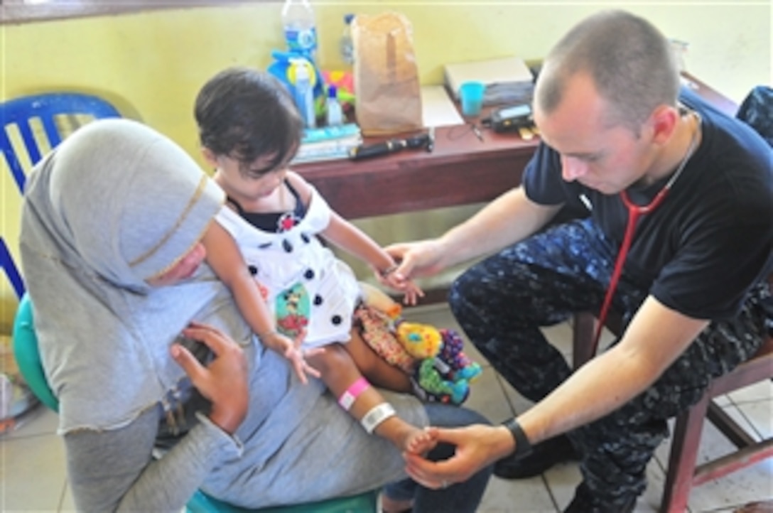 U.S. Navy Lt. Timothy Chinnock, embarked aboard the Military Sealift Command hospital ship USNS Mercy (T-AH 19), examines an infant's feet while her mother looks on during a Pacific Partnership 2010 medical civic action program in Tobelo, Indonesia, on July 15, 2010.  Pacific Partnership 2010 is the fifth in a series of annual U.S. Pacific Fleet humanitarian and civic assistance endeavors to strengthen regional partnerships.  