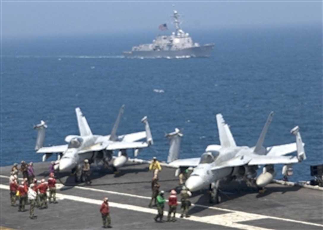 U.S. Navy sailors aboard the aircraft carrier USS George Washington (CVN 73) refuel F/A-18C Hornet strike fighter aircraft from Strike Fighter Squadron 195 while underway in the Sea of Japan as the guided missile destroyer USS Chung-Hoon (DDG 93) crosses in the background on July 27, 2010.  The George Washington is participating in the combined U.S. and South Korean maritime and air readiness exercise Invincible Spirit.  