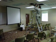 A 916th Communication Squadron Reservist puts up the cables for a projector while deployed to MacDill Air Force Base, Fla. (USAF photo courtesy 916CS)