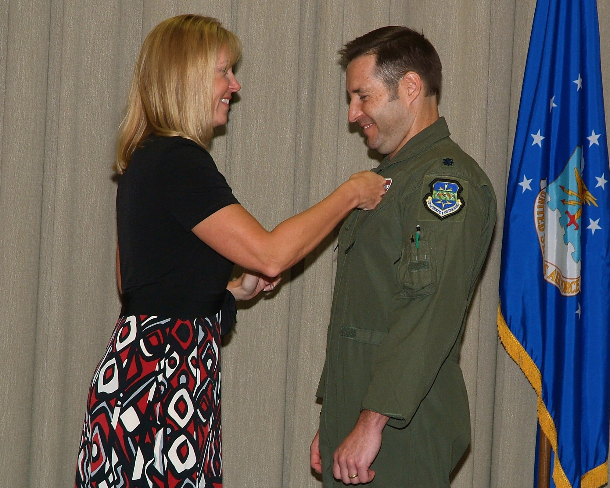 Amy Koncak (left) "pins" the Air Force Commander's Insignia on her husband, Lt. Col. Kyle Koncak during a change of command ceremony July 23 at Hurlburt Field, Fla. Col Mark Waite, 505th Training Group commander, presided over the ceremony. Colonel Koncak served as the 505th Training Squadron's operations director prior to assuming command of the 705th Training Squadron from Lt. Col. Gregory Yuen.  The 705th TRS conducts advanced academic training, education and mentorship to enhance operational-level air, space and cyberspace command and control for joint and coalition Warfighters. (U.S. Air Force photo by Keith Keel)