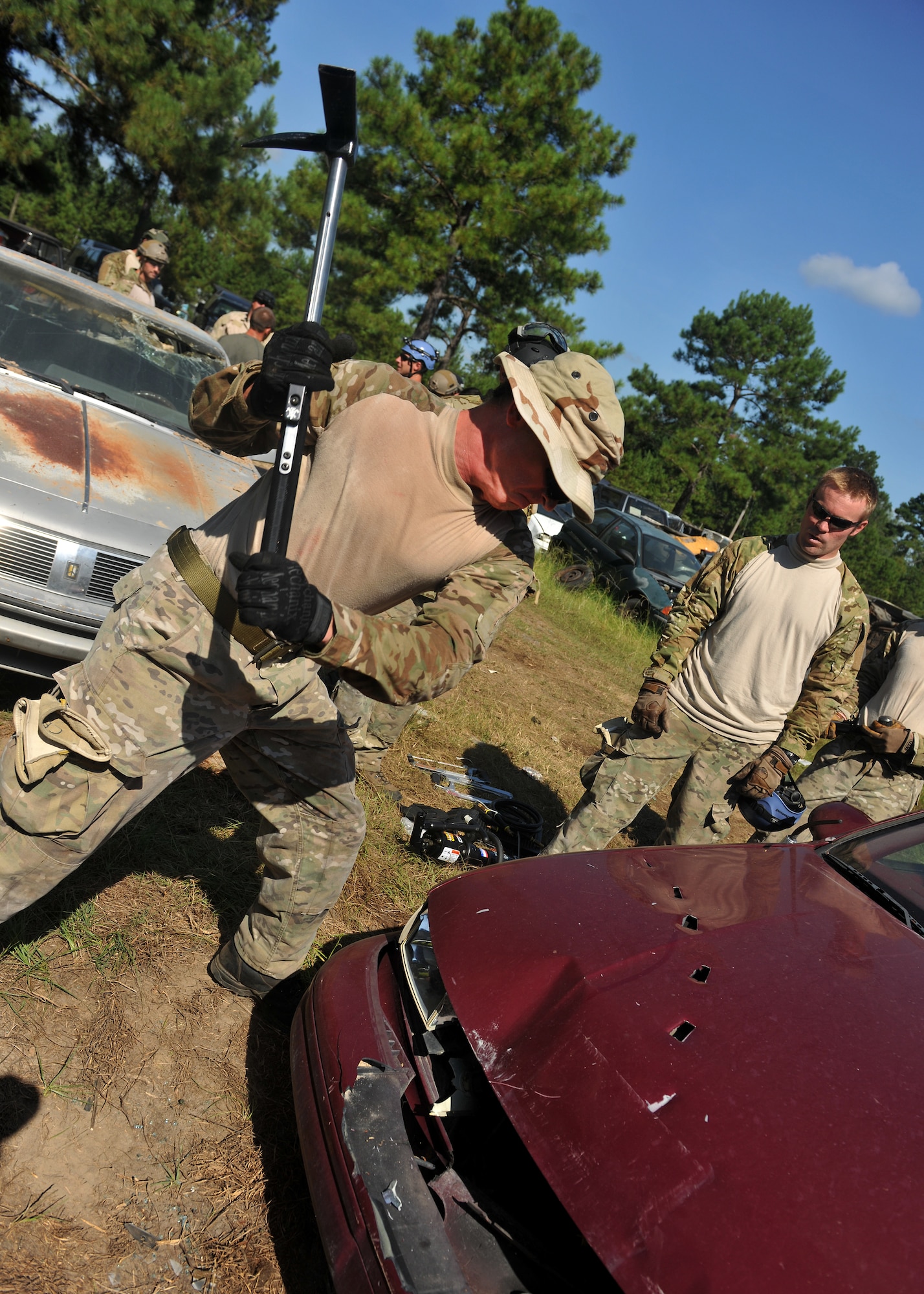 VALDOSTA, Ga. -- Senior Airman Clay Blakeney, 38th Rescue Squadron pararescueman from Moody Air Force Base, Ga., uses an axe to cut into the hood of a car during a confined spaces exercise at a local junkyard here July 27. In a real world situation involving a car crash, the first step is to remove the battery and cut the power. (U.S. Air Force photo by Airman 1st Class Joshua Green/RELEASED)