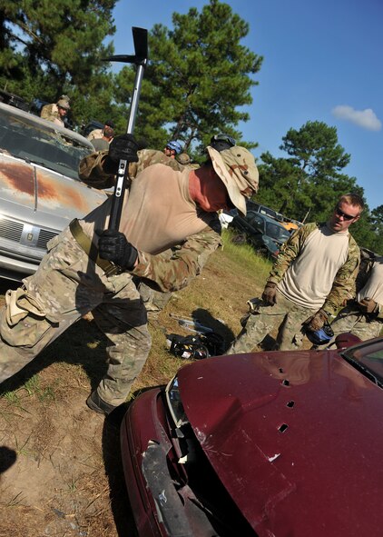 VALDOSTA, Ga. -- Senior Airman Clay Blakeney, 38th Rescue Squadron pararescueman from Moody Air Force Base, Ga., uses an axe to cut into the hood of a car during a confined spaces exercise at a local junkyard here July 27. In a real world situation involving a car crash, the first step is to remove the battery and cut the power. (U.S. Air Force photo by Airman 1st Class Joshua Green/RELEASED)