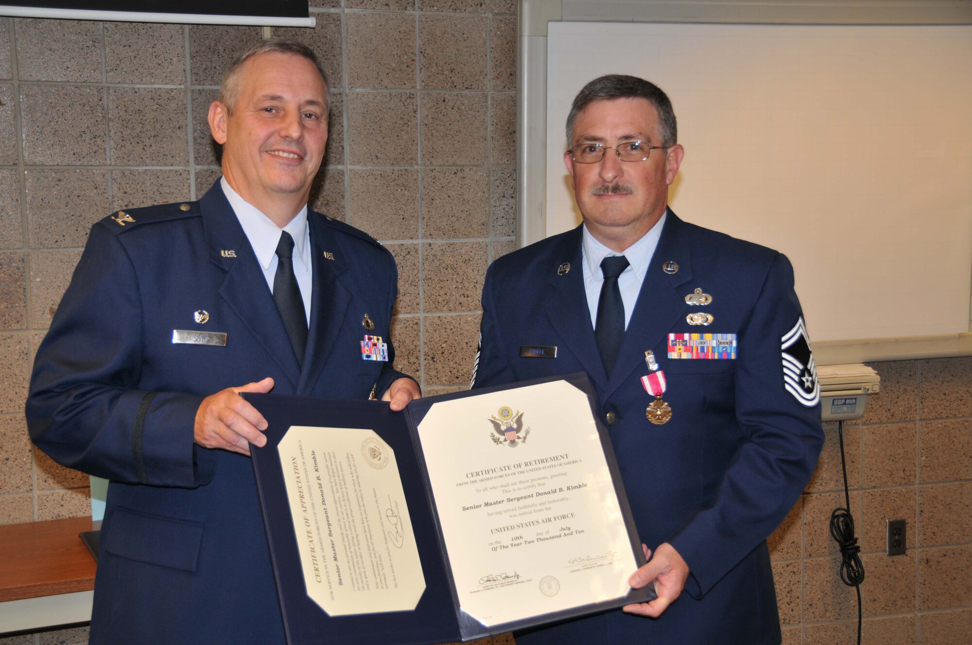 Senior Master Sgt. Brad Kimble (right) accepts his retirement certificate from Col. Mike Ochs, 934th Mission Support Group commander, July 10.  Sergeant Kimble retired with more than 29 years of service. (Air Force Photo/Tech.Sgt. Jeff Williams)