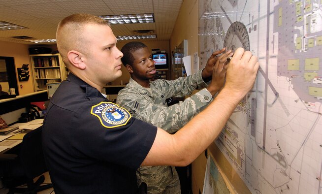 In the 72nd Security Forces Squadron’s Base Defense Operations Center, as all across base, military security forces work beside the DOD police officers.  Airman 1st Class Jonathan White and Officer Smith practice plotting a cordoned area as they would during a real-world emergency or an exercise. (Air Force photos by Margo Wright)