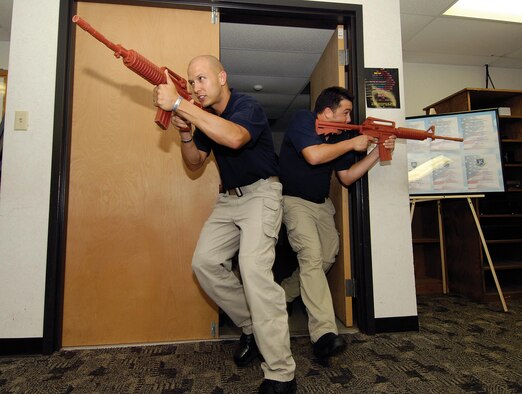 A team of new police officers, including Seth Ryan, left, and Brent Huddleston, burst into a room during an active-shooter scenario training session on base.  In more than 120 hours of initial training, the new officers will learn how to respond to domestic violence and child abuse situations, community oriented policing and use of force. (Air Force photos by Margo Wright)