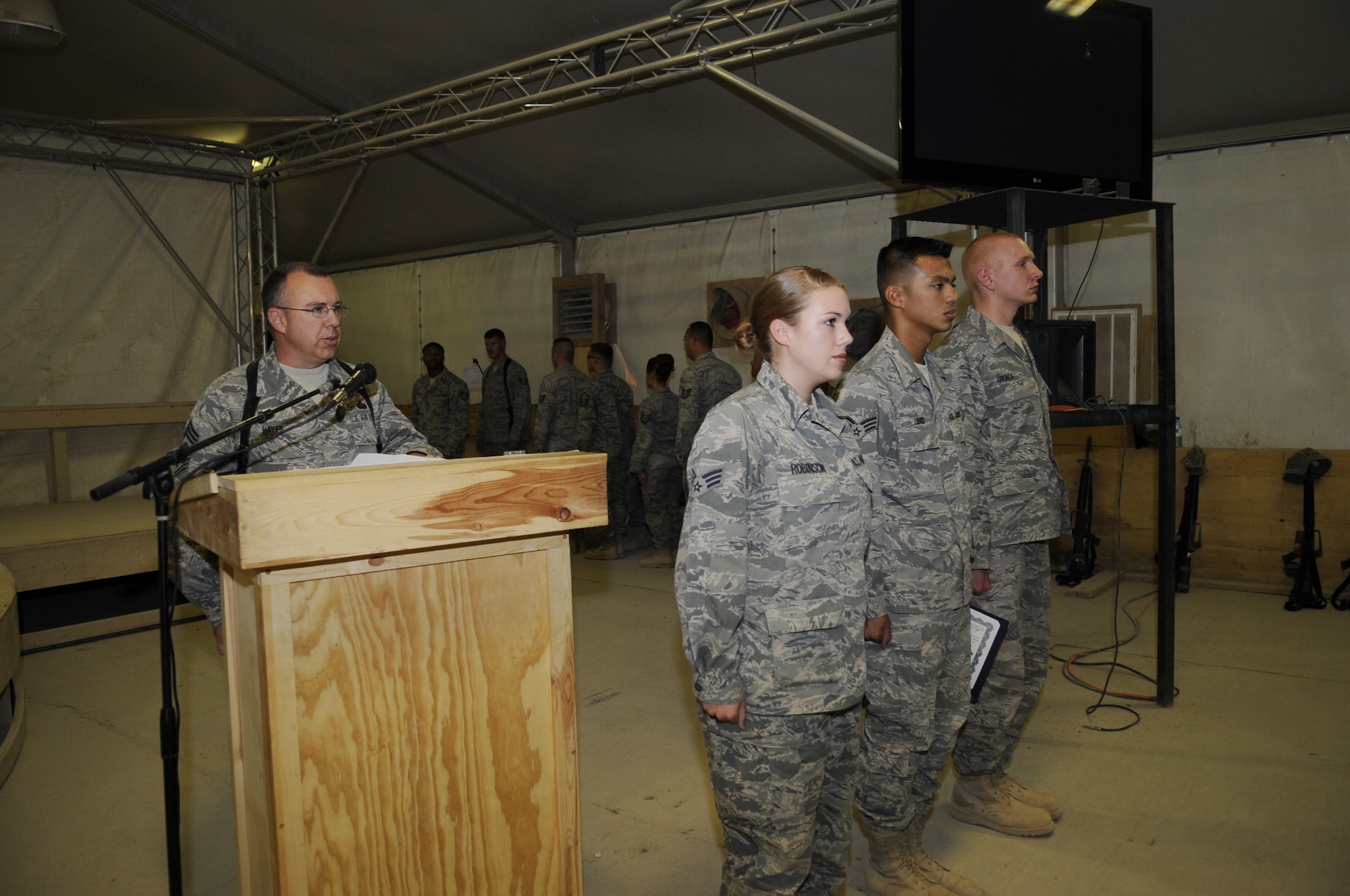 Chief Master Sgt. David G. Hayes, assigned to the 451st Expeditionary Communications Squadron, Kandahar Airfield, Afghanistan, reads the noncommissioned officer creed as his daughter, Senior Airman Ashley Robinson, and two other Airmen are promoted to staff sergeant during a ceremony at Kandahar Airfield, Afghanistan, June 30. All are assigned to the 451st Air Expeditionary Wing. (U.S. Air Force photo by Senior Airman Nancy Hooks)