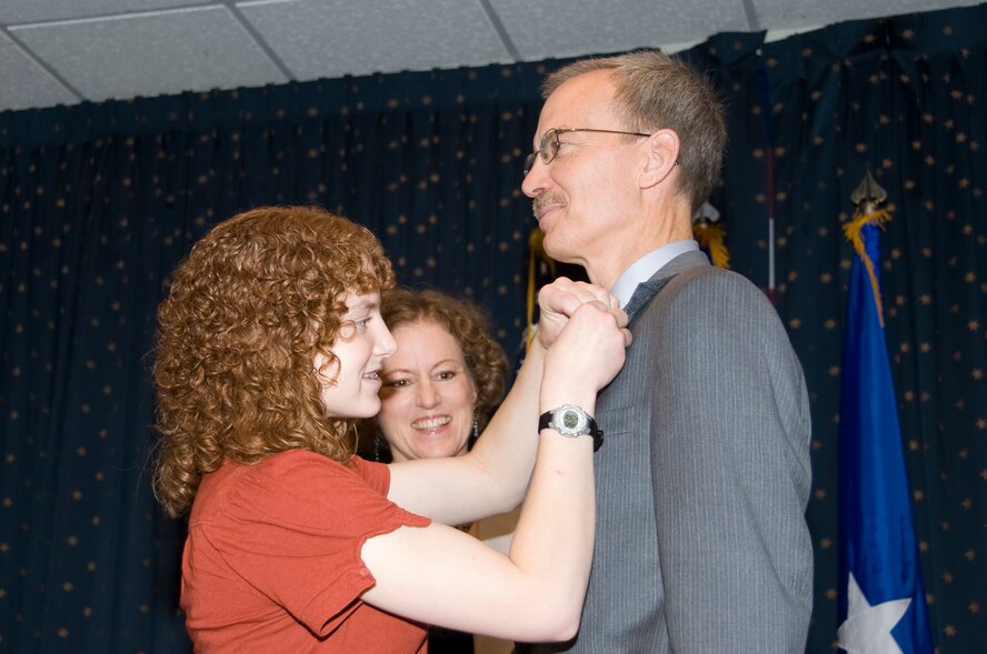 LeAnn Brasure watches as her daughter Alex pins a Senior Executive Service pin on her father, Dr. Wayne Brasure, during a promotion ceremony at the Mountain View Club July 21.  U.S. Photo by Elizabeth Martinez.