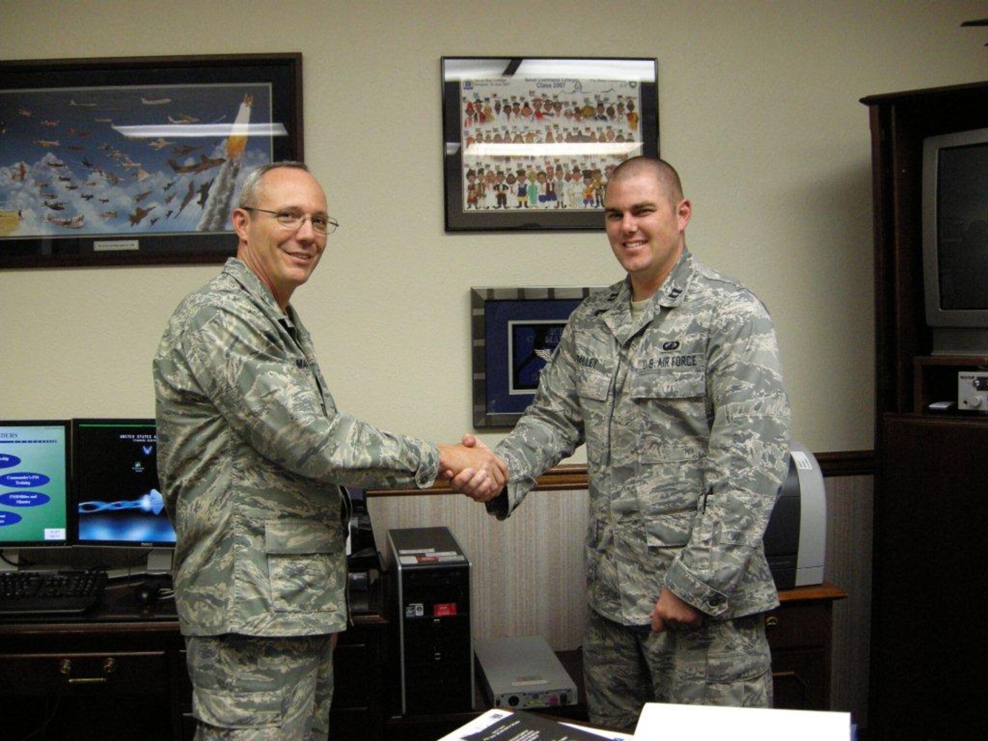 Col. Robert L. Maness, left, 377th Air Base Wing commander, presents a coin July 15 to Capt. Peter C. Talley, 377th Comptroller Squadron, for his development of the FM desktop reference.  U.S. Air Force photo by Marie Vanover.