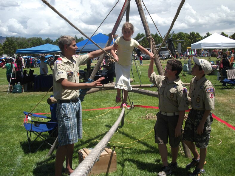 Kirtland Boy Scout Troop 85 and Cub Scout Pack 85 assist Hannah Covington, 5, in crossing the Monkey Bridge at this year’s Summer Bash.  U. S. Air photo by Jasmine Simon
