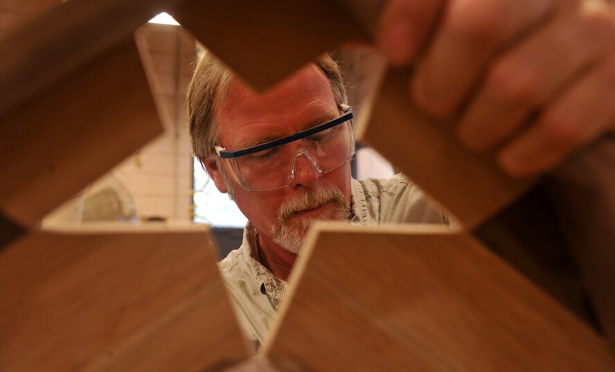 MOODY AIR FORCE BASE, Ga. -- Jim Connelly, Wood Shop supervisor, uses sandpaper to smooth the edges of a shadow box shaped like the Air Force insignia here July 9. After the pieces of wood are cut and put together, the shadow box has to be sanded to a smooth texture before having the finishing coat applied. (U.S. Air Force photo by Airman 1st Class Joshua Green/RELEASED)