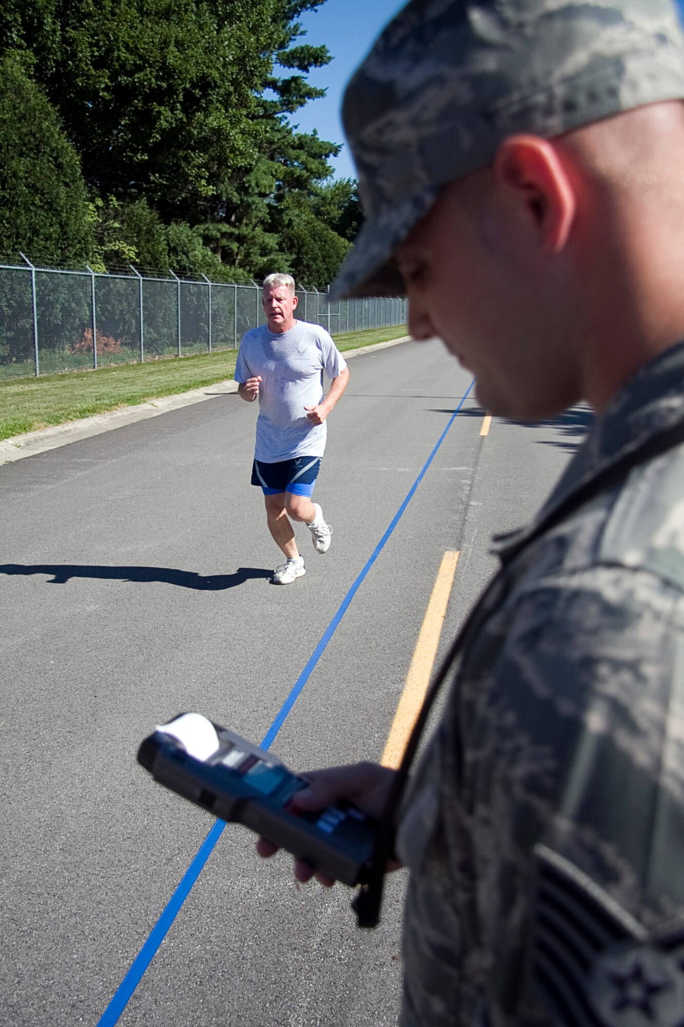 GRISSOM AIR RESERVE BASE, Ind. -- Senior Master Sgt. Richard Scully races to the finish line during a fitness test held here recently as Tech. Sgt. Traey Corbin clocks in his time. Starting in July, the Air Force implemented new fitness assessment standards, which now include bi-annual testing, minimum requirements within testing components and establishing fitness assessment cells to proctor tests. The aerobic component counts for 60 of the possible 100 points. Sergeant Scully is a chief of quality assurance with the 434th Maintenance Group, and Sergeant Corbin is a services specialist with the 434th Services Flight. (U.S. Air Force photo/Tech. Sgt. Mark R. W. Orders-Woempner)