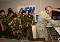 KUNSAN AIR BASE, Republic of Korea -- Senior Airman Steve Conklin, Armed Forces Network Korea at Kunsan, performs a mock radio show while Republic of Korea students from Jik Island watch during their visit here July 29. The students also toured the 8th Operations Support Squadron air traffic control tower during their visit. The visit was documented by both AFN and the Korean Forces Network. (Republic of Korea Air Force photo/Courtesy photo)