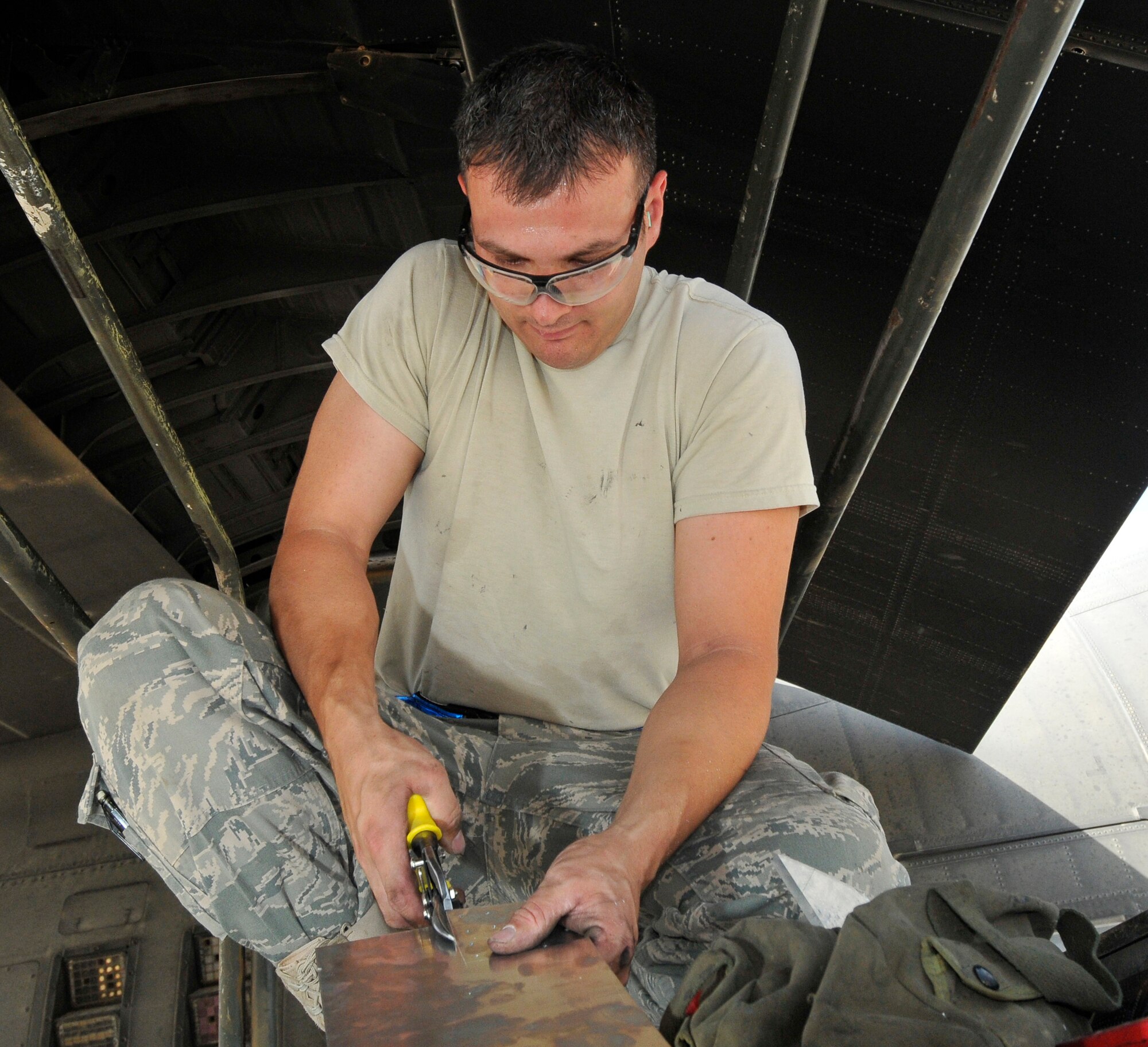 Staff Sgt. Francisco Velasquez, 332nd Expeditionary Maintenance Squadron aircraft structural maintenance craftsman, uses a hand-held metal shear to cut a patch from a sheet of aluminum to cover a crack in a C-130 Hercules wing baffle July 24, 2010, Joint Base Bald, Iraq. The ability to cut and form metal on the spot aids in rapid mission repairs and efficient maintenance operations. Sergeant Velasquez is a native of Monroe, Mich., deployed from Little Rock Air Force Base, Ark. (U.S. Air Force photo/Staff Sgt. Phillip Butterfield)