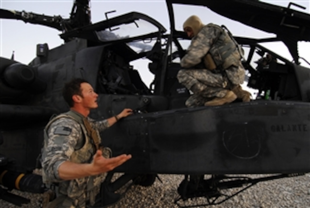 U.S. Army Chief Warrant Officer 2 Mark Davis (left) and Chief Warrant Officer 3 Mike Croslin discuss their last mission after landing an AH-64 Apache helicopter from Company B, 1st Battalion, 4th Aviation Regiment, Attack Reconnaissance Battalion in Kunduz, Afghanistan, on July 24, 2010.  The Apache landed to refuel after a firefight with insurgents.  