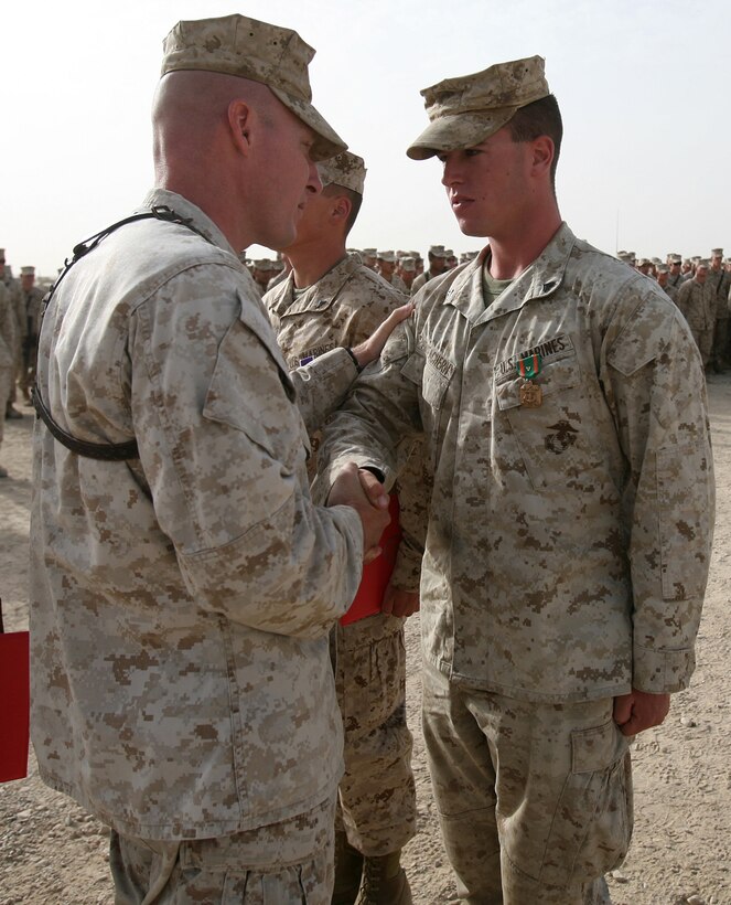 Corporal Rory MacEachern, a military policeman with Combat Logistics Battalion 6, 1st Marine Logistics Group (Forward), is congratulated by his commanding officer, Maj. William Stophel, upon being awarded the Navy and Marine Corps Achievement Medal with Combat Distinguishing Device here, July 30. During combat logistics patrols ranging from March through May, the North Attleboro, Mass., native, distinguished himself through superior performance of his duties as a machine gunner. On more than one occasion MacEachern was able to effectively eliminate enemy threats with precision fire from his position as a gunner, allowing each combat logistics patrol to continue safely.