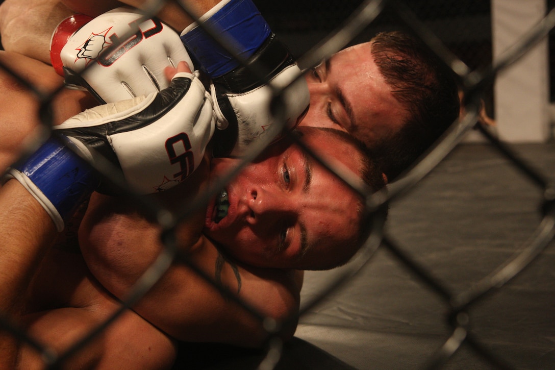 Tony Wojak (top), of Team Wrights Extreme Martial Arts, works a choke into Robert Abrantes, of Team Corps, during the Sacred Ground Mixed Martial Arts event at Goettge Memorial Field House aboard Marine Corps Base Camp Lejeune, July 31.