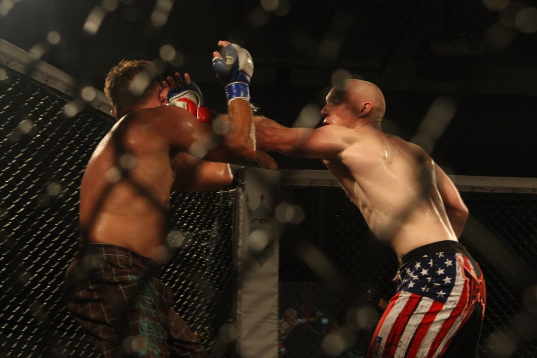 Josh Plato (right), of Team Corps, delivers a left jab to Ryan Christensen, of Team Evolution Mixed Martial Arts, during the Sacred Ground Mixed Martial Arts event at Goettge Memorial Field House aboard Marine Corps Base Camp Lejeune, July 31.