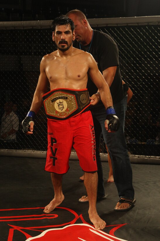 Cesar Llamas, of Team Elite Combat, is awarded with the Carolina Fight Promotions Featherweight World Title belt after defeating Preston Marks, of Team Joe Hurst Brazilian Jiu-Jitsu, during the Sacred Ground Mixed Martial Arts event at Goettge Memorial Field House aboard Marine Corps Base Camp Lejeune, July 31.