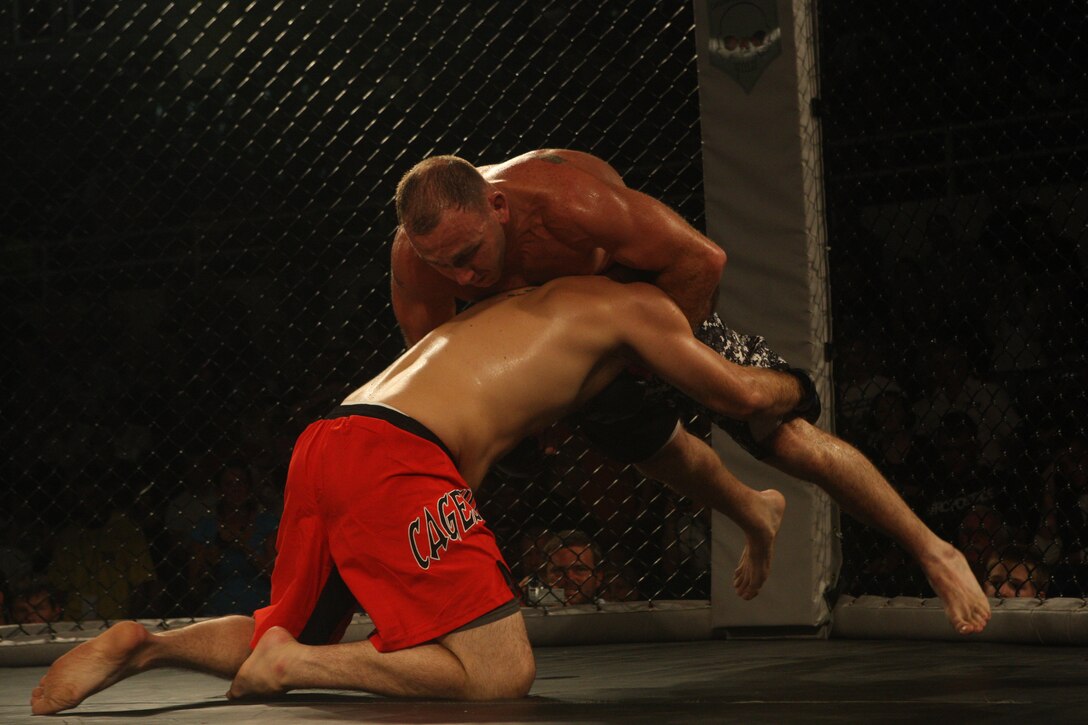 Gunnery Sgt. Paul Wright (above), academics chief for the School of Infantry - East aboard Camp Geiger, N.C., locks in a submission headlock on Jake Whitfield, a professional mixed martial arts fighter, during the Sacred Ground MMA event aboard Marine Corps Base Camp Lejeune, July 31. Wright has been practicing MMA since he joined the Marine Corps in 1996, utilizing it as a tool in both his personal growth and his progression through the Marine Corps.