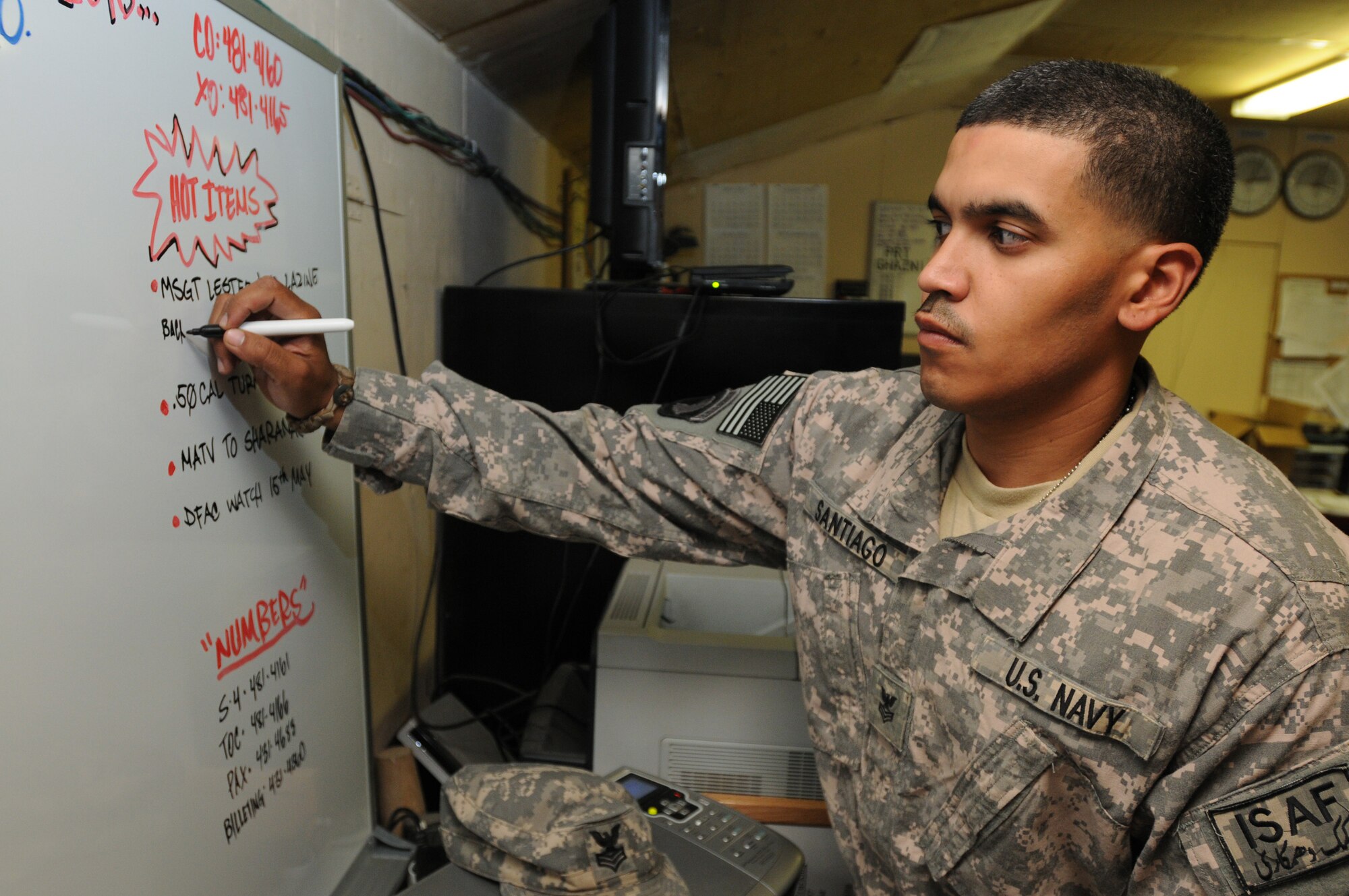 Petty Officer First Class Wilson Santiago writes notes on his reminder board May 8, 2010, at Bagram Airfield, Afghanistan.  He is a member of the Paktika Provincial Reconstruction Team but currently is assigned to Bagram as a liaison officer. Petty Officer Santiago, a native of Irvington, N.J., is deployed from the USS George H. W. Bush. (U.S. Air Force photo/Master Sgt. Demetrius Lester)