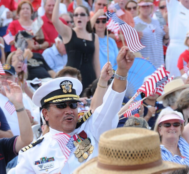 A Navy service member waves his flag while the song "God Bless America" is performed by the Navy Band Southeast at a ceremony held on Memorial Day at the Jacksonville Veterans Memorial Wall in downtown Jacksonville Fla. (Air National Guard photo by Staff Sgt. Jaclyn Carver)