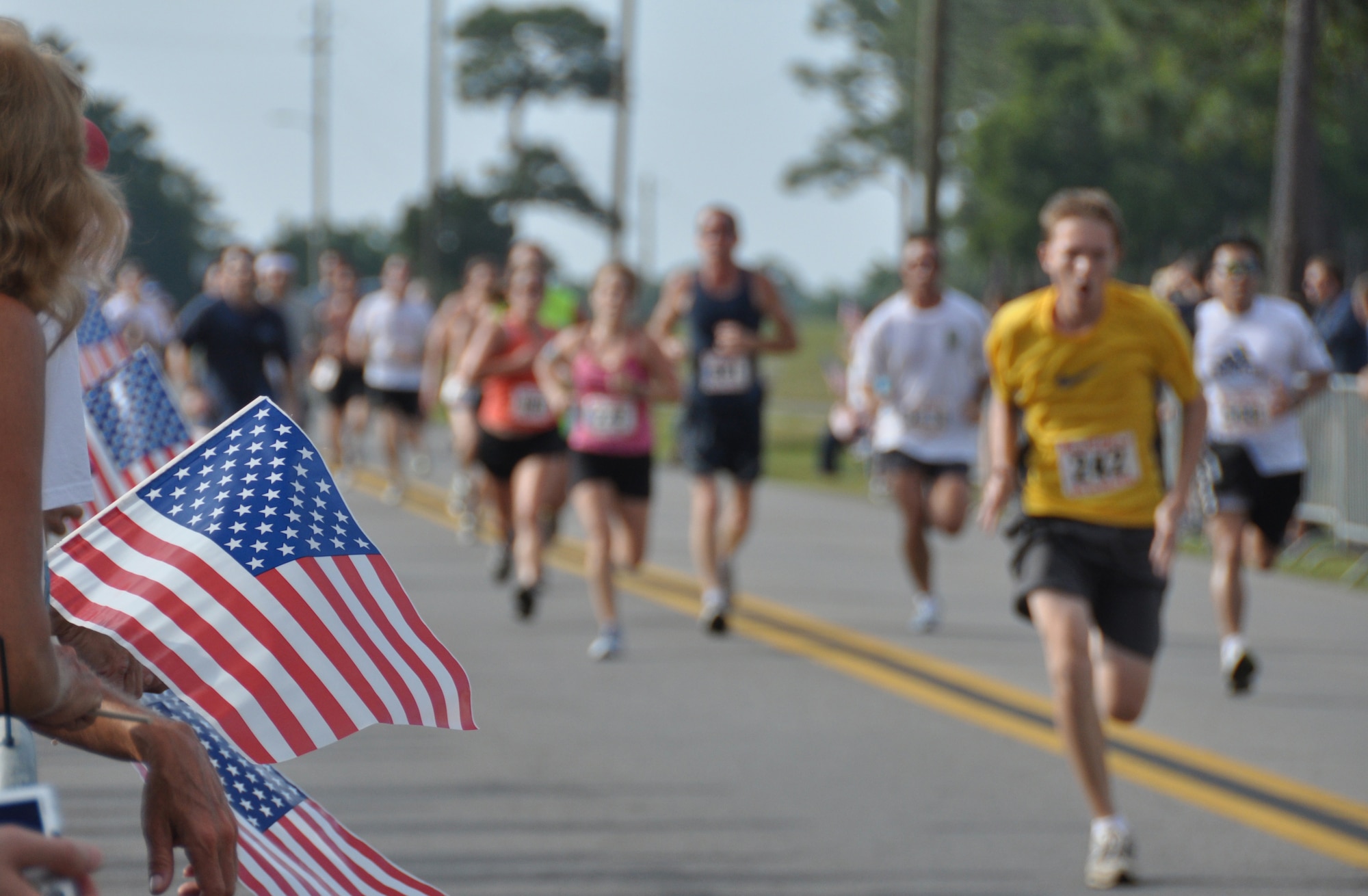 Supporters wave flags and cheer on runners as they approach the finish line during the 4.4 mile Gate-to-Gate run/walk held annually on Memorial Day at Eglin Air Force Base, Fla.  (U.S. Air Force photo/Staff Sgt. Stacia Zachary) 