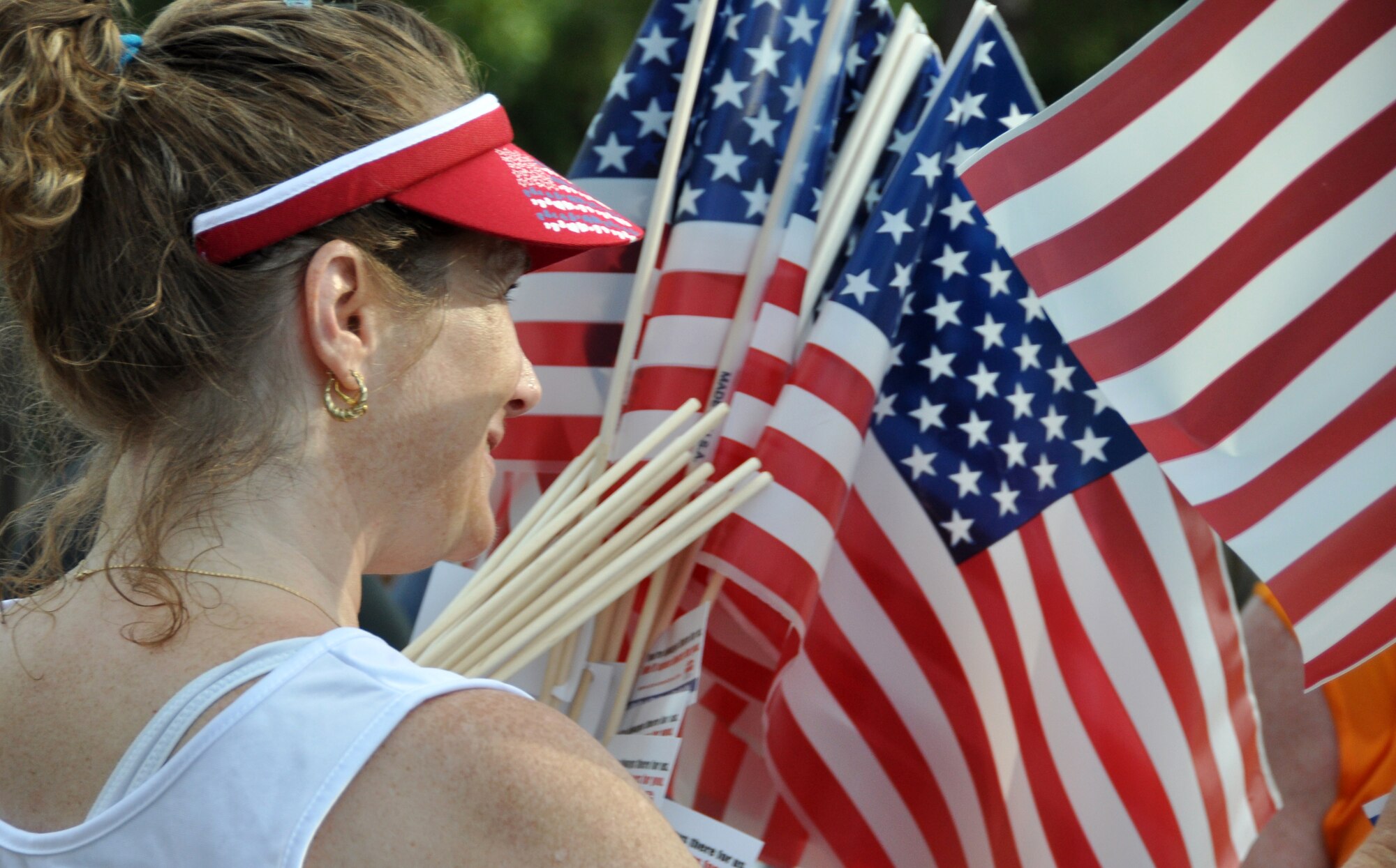 A volunteer hands out American flags to the runners upon completion of the 4.4 mile Gate-to-Gate run/walk held annually on Memorial Day at Eglin Air Force Base, Fla.  (U.S. Air Force photo/Staff Sgt. Stacia Zachary) 