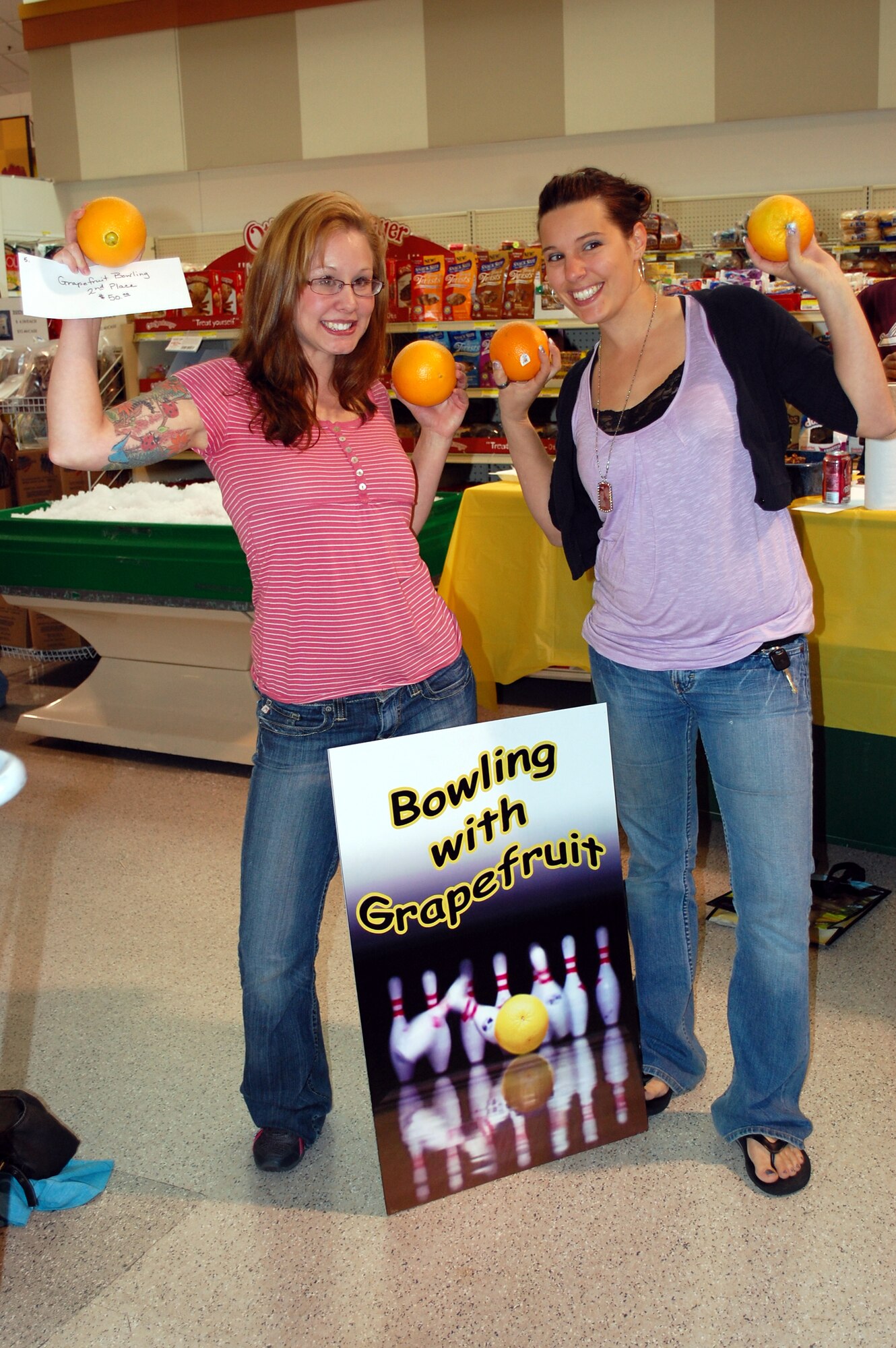 Oranges substituted for grapefruits in the bowling with fruit game May 23 during Deployed Spouse's Night activities. Second palce winner Megan Cornielle (left) won $50 in commissary gift cards and first place winner Melissa Bertrand (right) won $100 in commissary gift cards. (U.S. Air Force photo/Valerie Mullett)