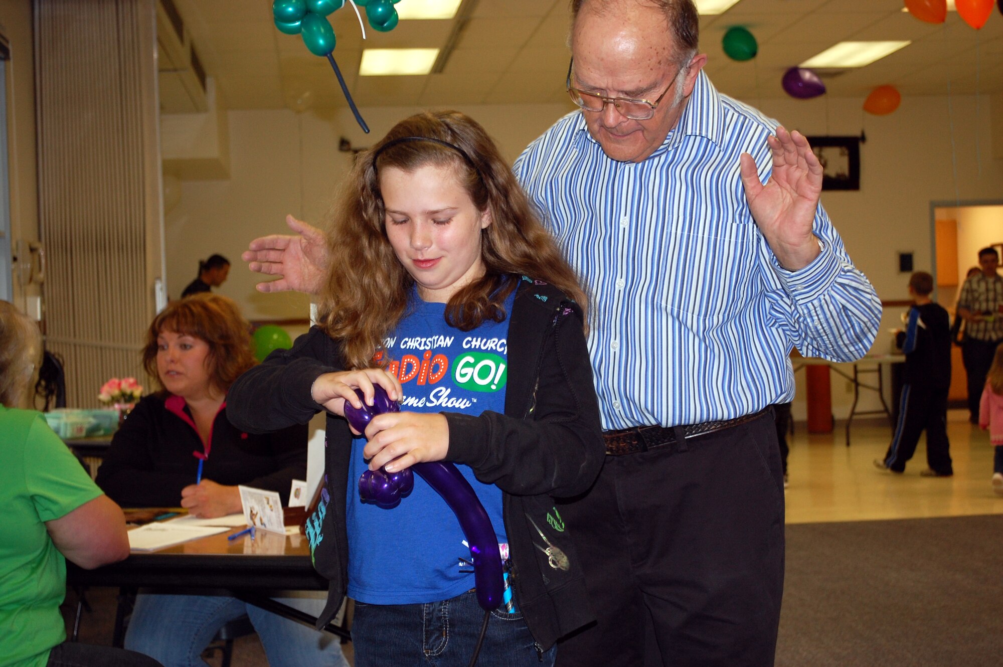Frank King, Vacation Bible School chairperson for Grace Baptist Church, teaches 10-year-old Danielle Vander Kaay how to make a dog our of a balloon during the chapel's VBS Fair May 22. Twleve programs, including Malmstrom's, were offered for parents to sign their children up for this summer. (U.S. Air Force photo/Valerie Mullett)