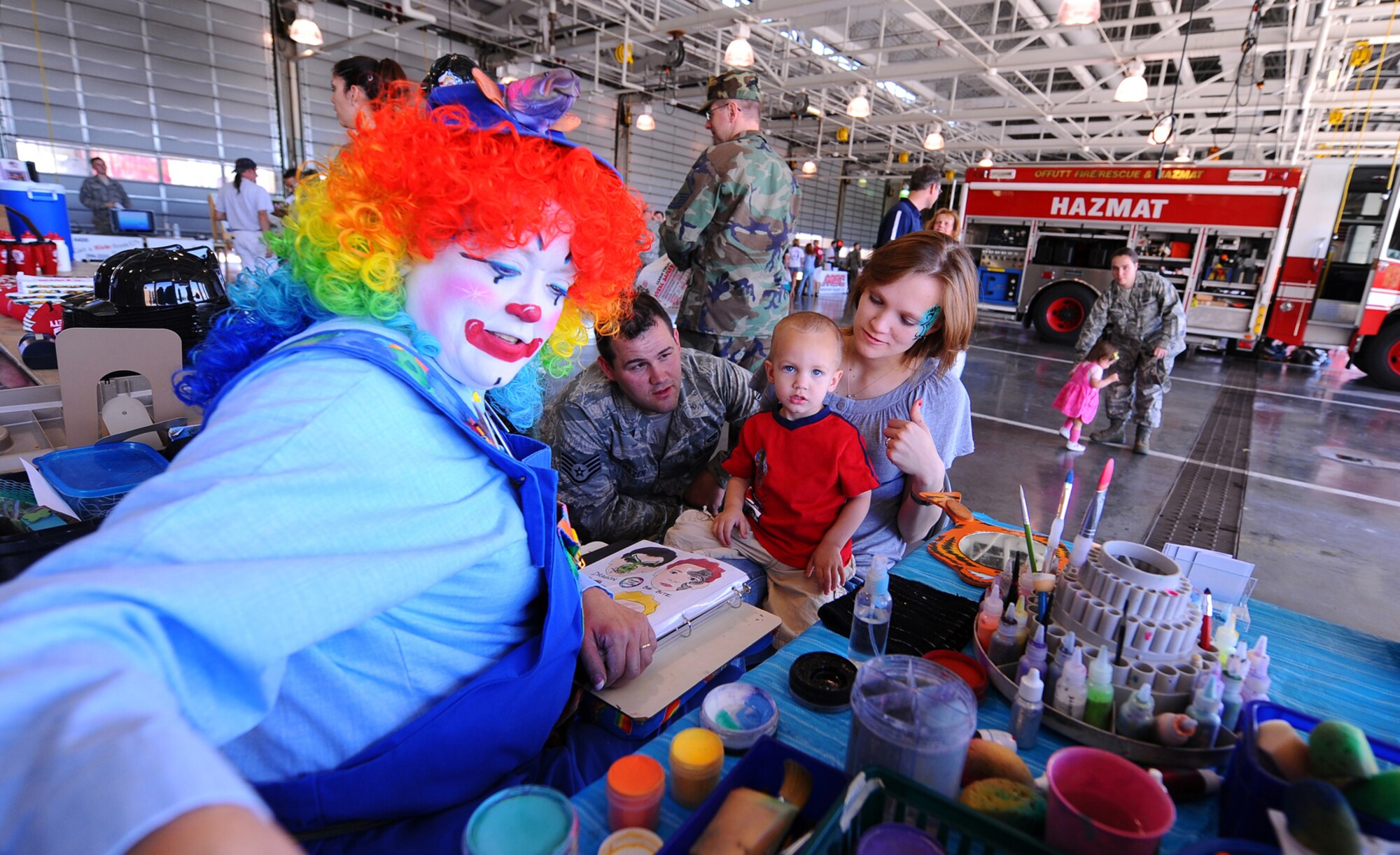 OFFUTT AIR FORCE BASE, Neb. -- Rainbow Trout, a face painting and balloon artist clown, prepares to transform two year old Jace Hazen, son of Staff Sgt. Aaron Hazen with the 55th Maintenance Squadron, into a green dragon as part of Wing Safety Day at the Offutt Fire Department here May 27. During the event, numerous vendors gave useful information to attendees that focused on staying safe during the summer. U.S. Air Force Photo by Josh Plueger
