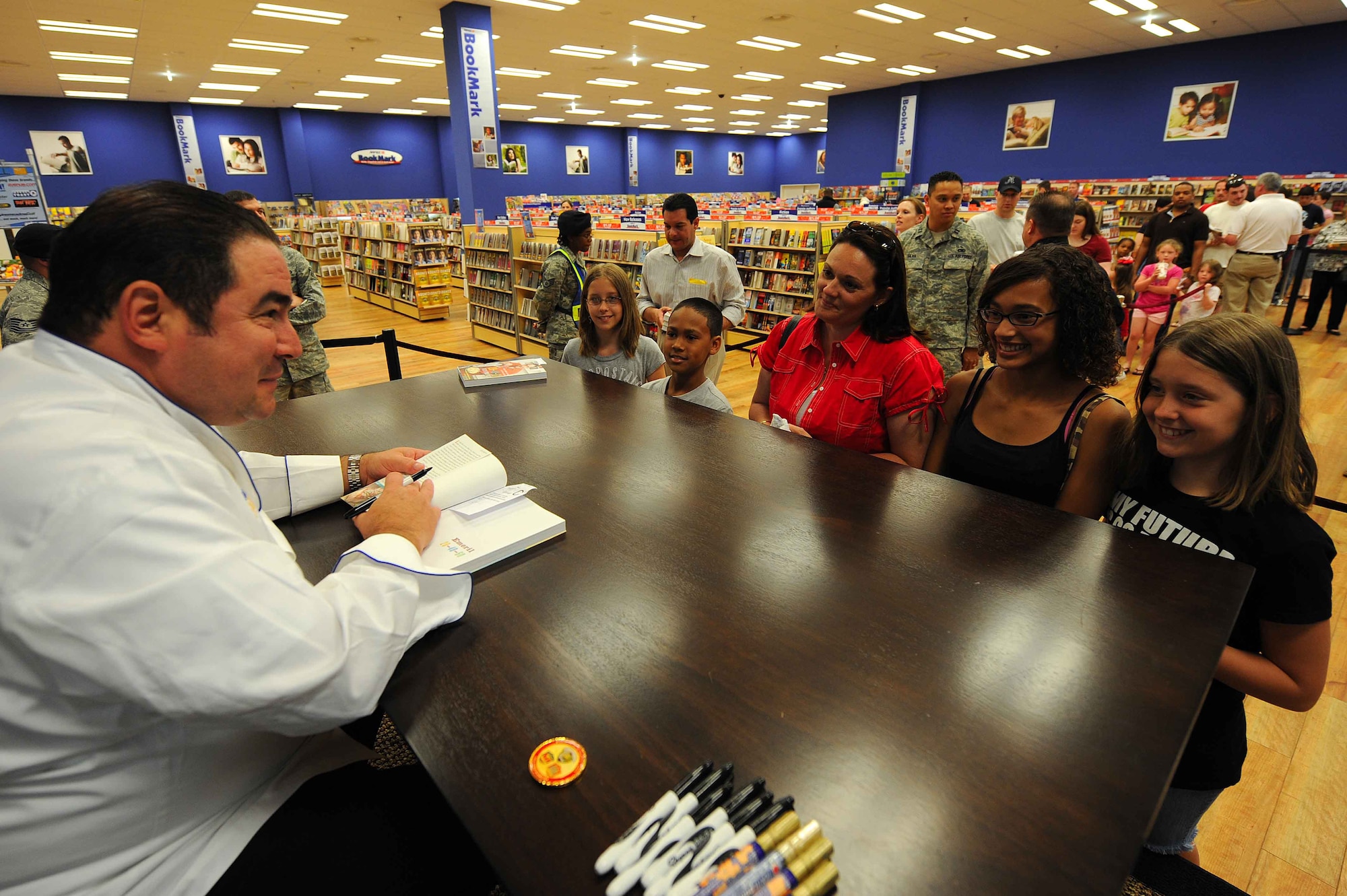 Celebrity Chef Emeril Lagasse signs copies of his cookbooks for fans at the Kaiserslautern Military Community Center, Ramstein Air Base, Germany, May 29, 2010. Emeril Lagasse visited the KMCC to promote his new book along with providing a book signing and a full production cooking exhibition copies of his new book and performing an hour long cooking demonstration for over a thousand visitors. (U.S. Air Force photo by Staff Sgt. Stephen J. Otero)