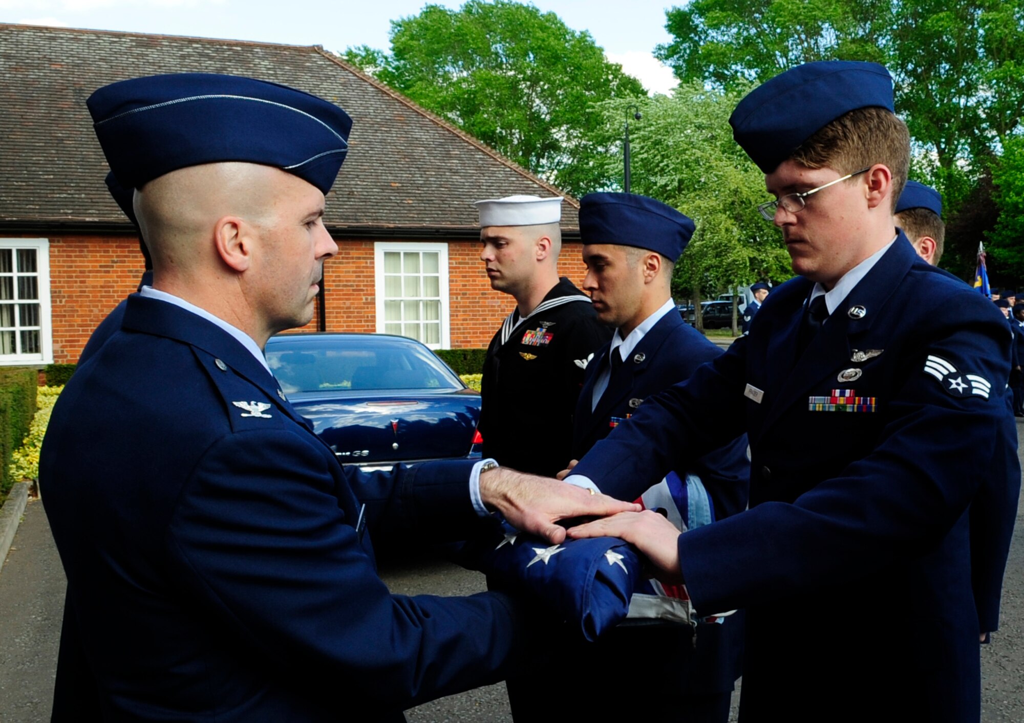 RAF MILDENHALL, England – Col. Chad Manske, 100th Air Refueling Wing commander, receives a flag from Senior Airman Ryan Frazier, 488th Intelligence Squadron, during Retreat May 28.  The Retreat ceremony signals the end of the duty day and also pays respect to the flag.  (U.S. Air Force photo/Staff Sgt. Christopher L. Ingersoll)