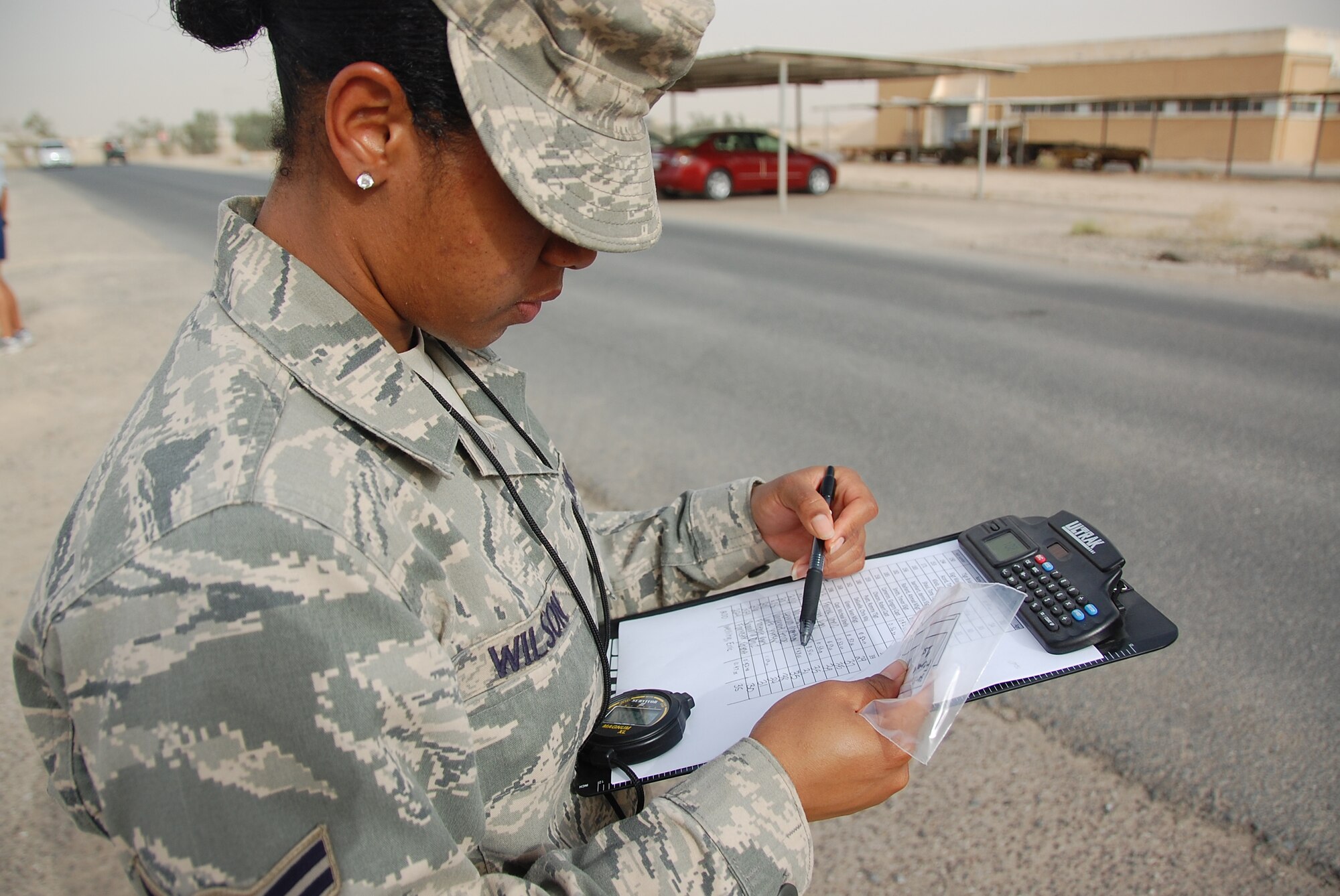 U.S. Air Force Airman 1st Class Delicia Wilson of the 386th Expeditionary Civil Engineer Squadron checks in runners at the finish line of a Memorial Day 10K May 31, 2010 at an air base in Southwest Asia. The 386th Expeditionary Force Support Squadron hosted the early morning run with the help of volunteers such as Airman Wilson. (U.S. Air Force photo by Tech. Sgt. Lindsey Maurice/Released)