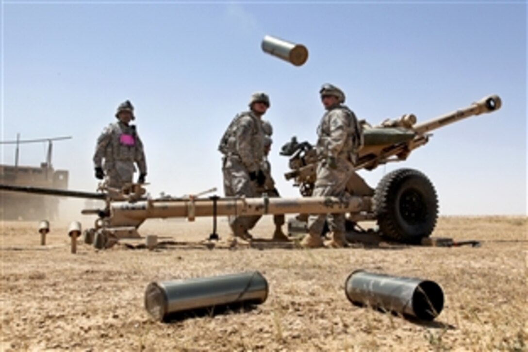 U.S. Army Pfc. Mark Ayers stands ready to dispose of spent brass during a artillery live fire qualification range on Memorial Range, Contingency Operating Base Speicher, Iraq, May 21, 2010. Ayers is assigned to Alpha Battery, 2nd Battalion, 32nd Field Artillery. The soldiers are required to conduct range qualification to keep the fire team's accuracy and timing at its best.