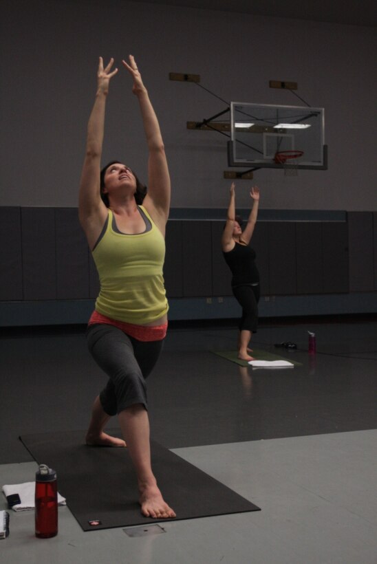 Trisha Kelly, an aerobics instructor, leads a group of women through a power yoga class at the Community Center, June 2. Power yoga is one of many aerobics workout routine available to the Combat Center community through the Aerobics Program.