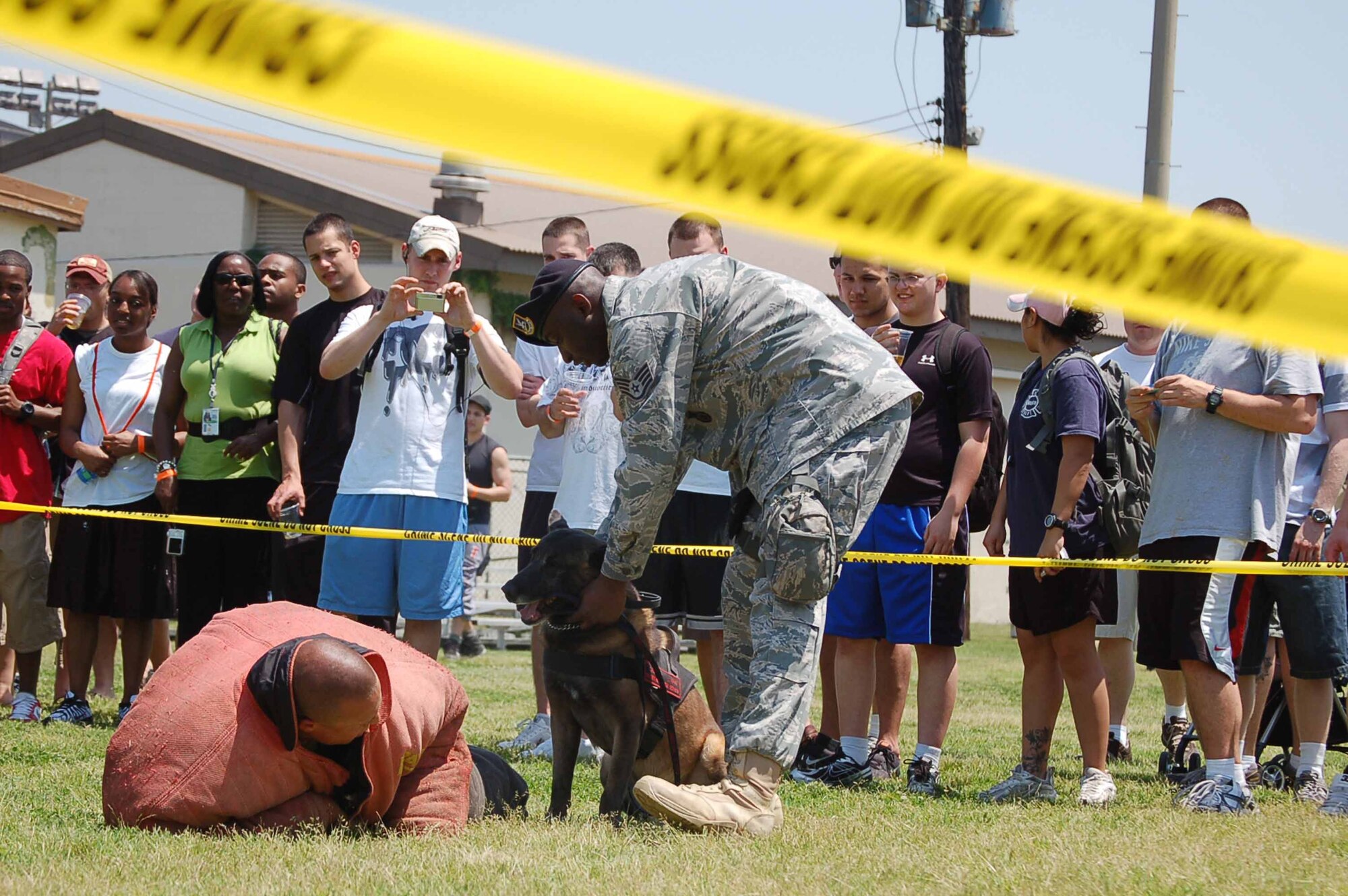 KUNSAN AIR BASE, REPUBLIC OF KOREA--The  crowd looks on as Staff Sgt. Anthony Vick of the  8th Security Forces Squadron pats Rico, his military working dog, after Rico subdued a “suspect” during a MWD demonstration at the 8th Fighter Wing Junior Enlisted Appreciation Day May 21.  The Kunsan Top Three Association sponsored the day of music, sports, food and fun as a way to thank junior enlisted members for the hard work they do every day to accomplish the wing mission.  (U.S. Air Force Photo/Master Sgt. Anna Hayman)