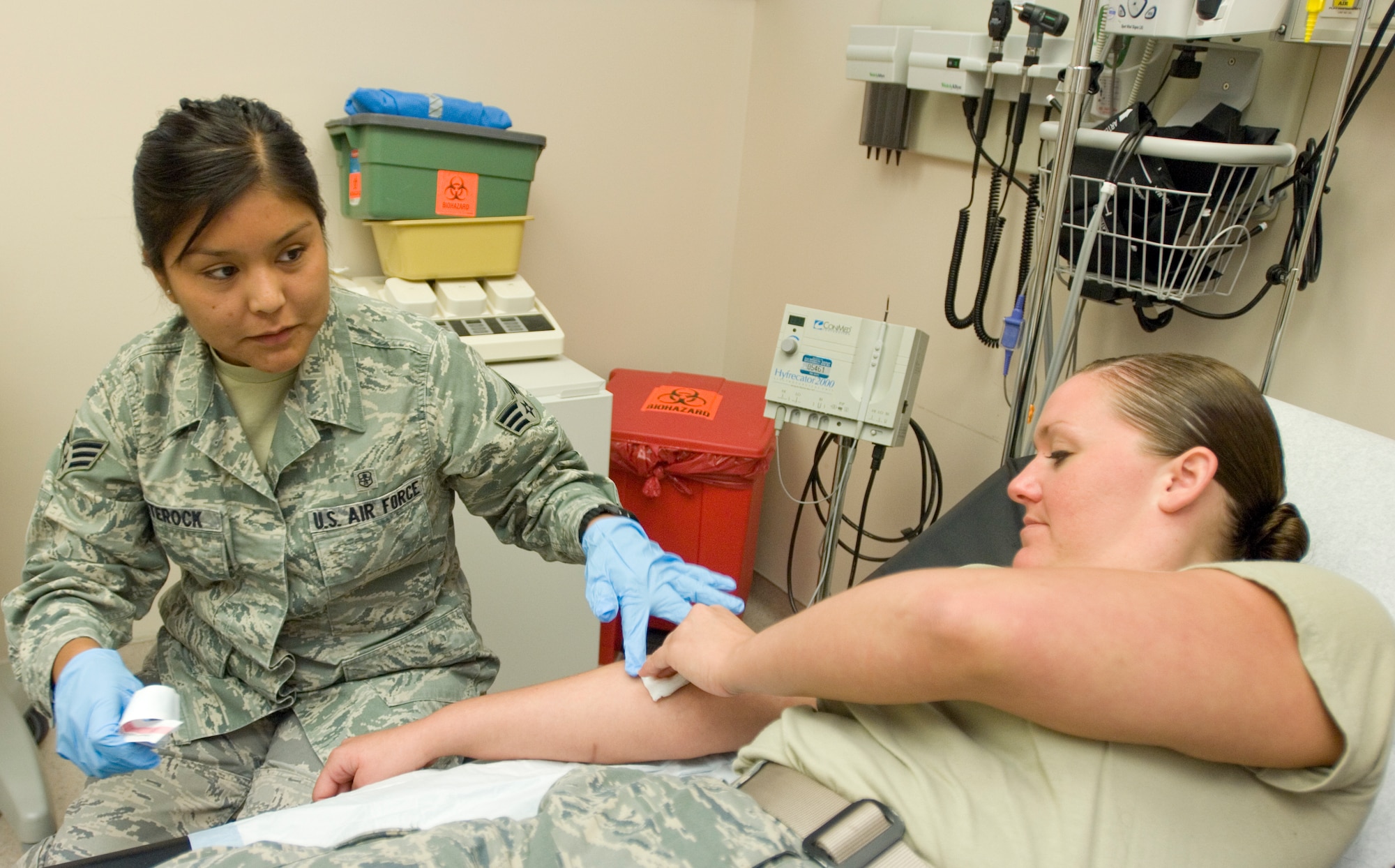 Senior Airman Crystal Whiterock, 22nd Medical Operations Squadron medical technician, applies pressure to Senior Airman Christina Begeal’s, 22nd MDOS medical technician, arm after sticking her with a needle as part of her weekly training.  In addition to taking blood, Airman Whiterock is a certified emergency medical technician and is responsible for screening  patients and assisting doctors with any procedures at the base clinic.  (U.S. Air Force photo/Senior Airman Abigail Klein)