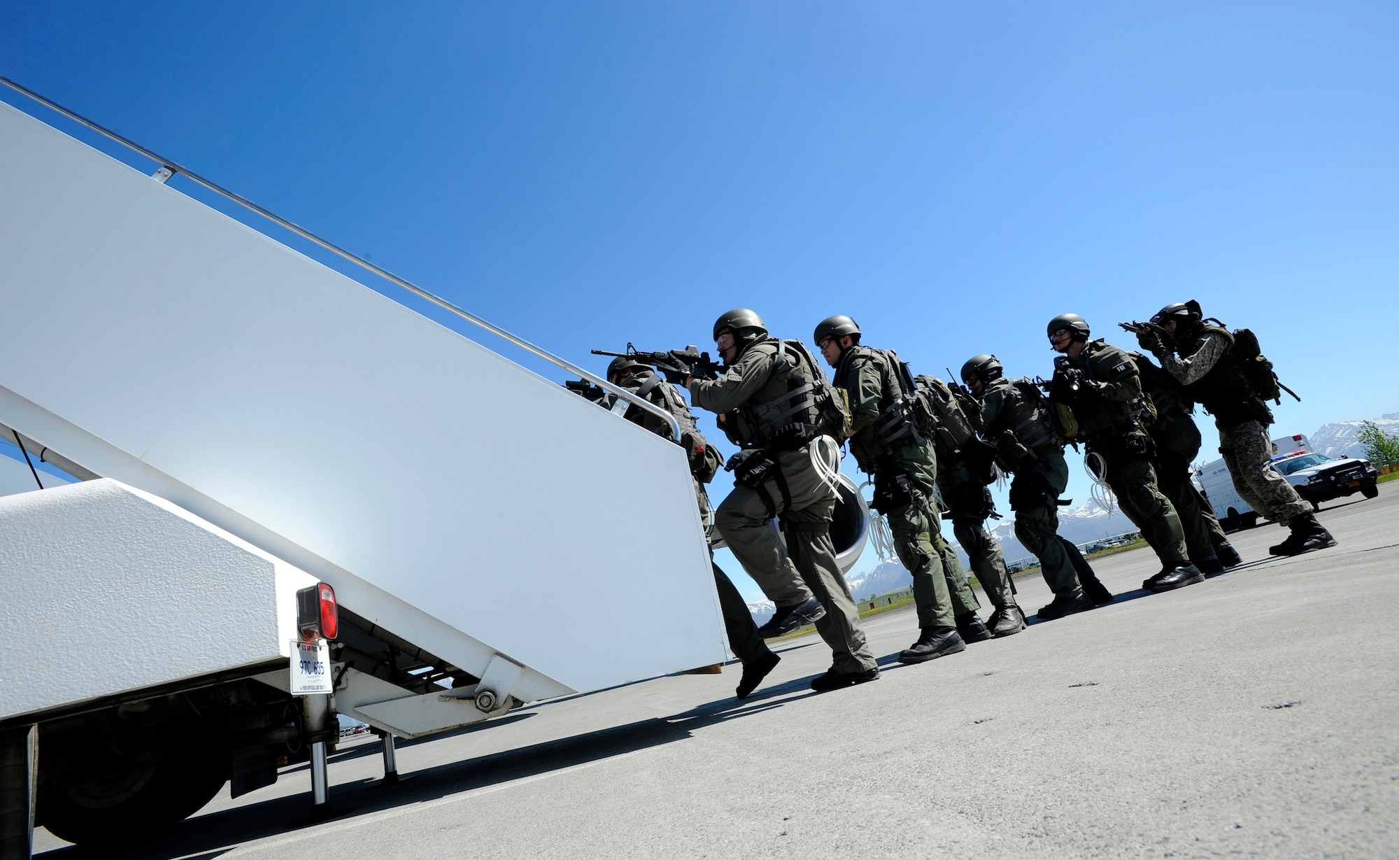 A Federal Bureau of Investigation and Alaska State Trooper joint SWAT team move toward an aircraft during Arctic Fencing Inter-Agency Arrow 2010 field training exercise May 26. During this exercise Department of Defense, Department of Justice and Department of Homeland Security personnel worked together to resolve a simulated terrorist hijacking of a commercial aircraft from the initial in flight tactical response until the aircraft was safely escorted to the airport and secured by agents on the ground. (U.S. Air force photo/Staff Sgt. Brian Ferguson)